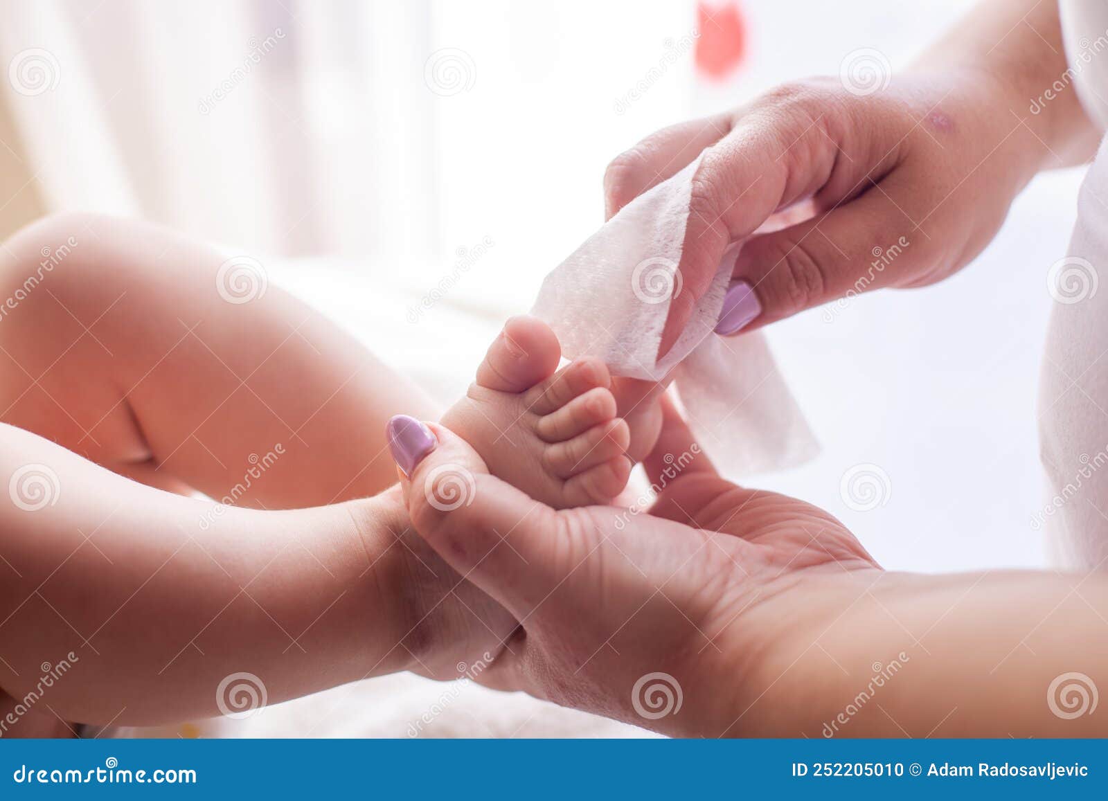 the mother takes care of the baby skin and wipes the baby`s feet with wet wipes