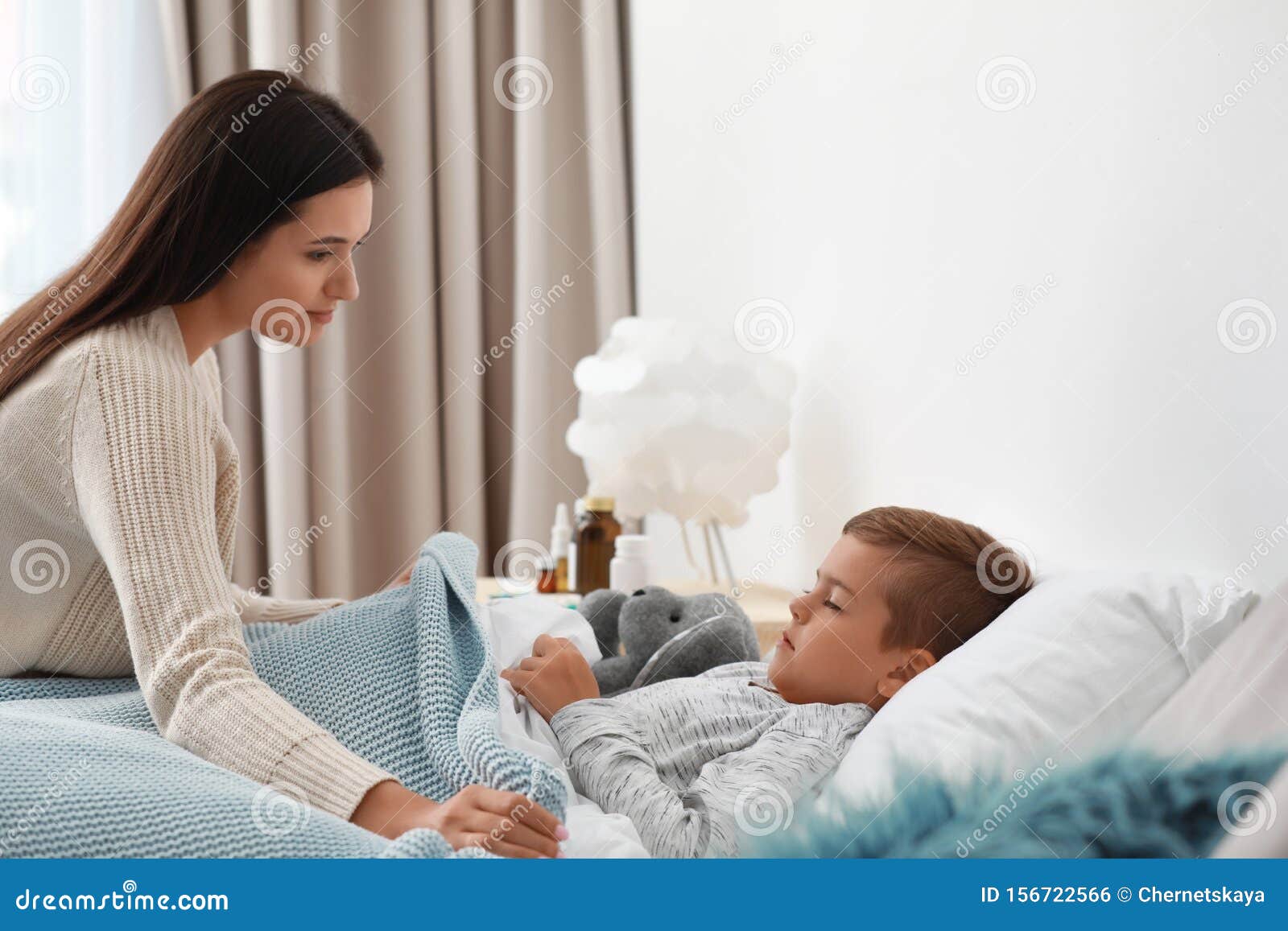 Mother Taking Care Of Her Little Son Suffering From Cold Stock Photo