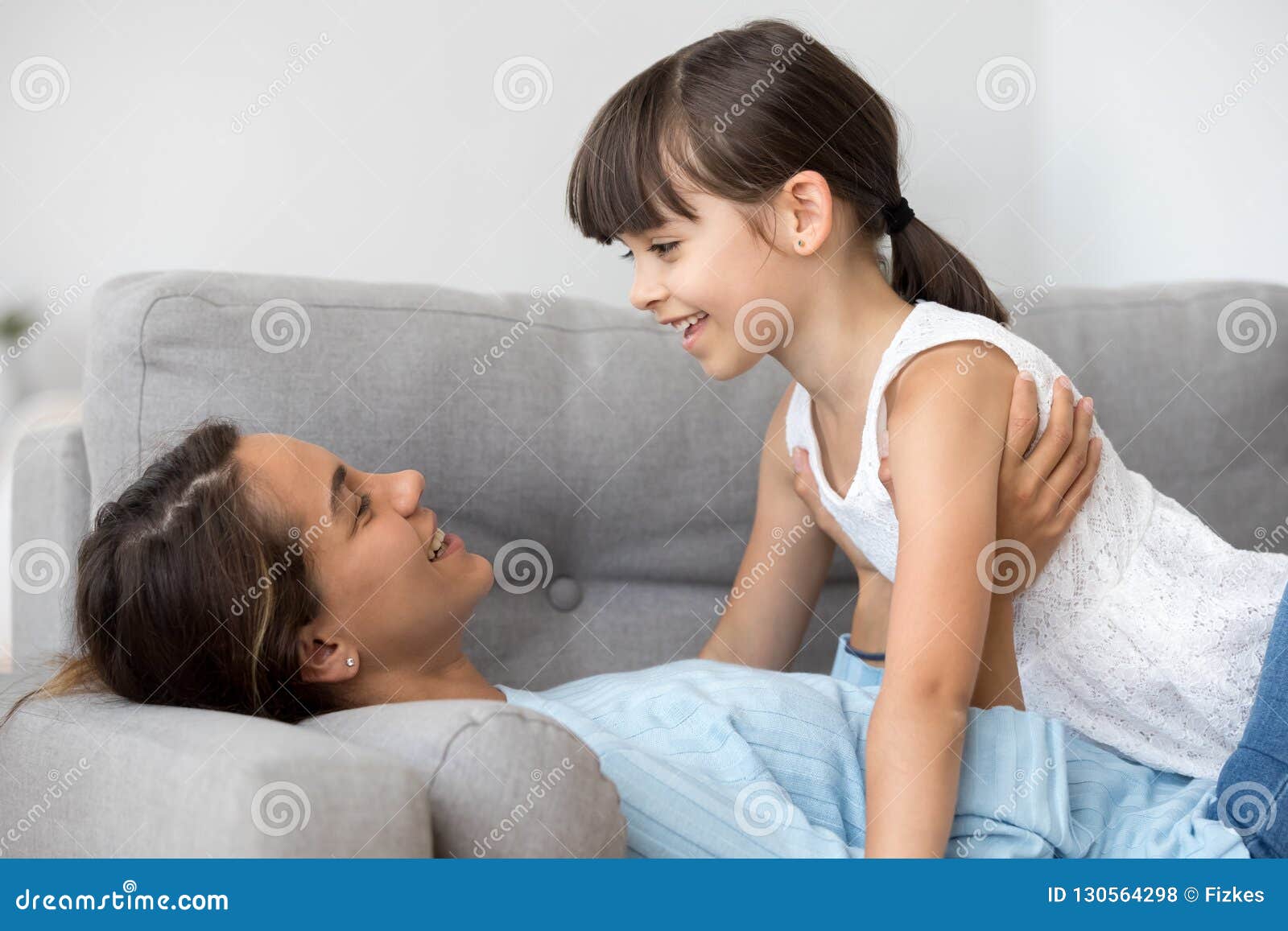 Mother Talking With Daughter Lying Together On Sofa Stock