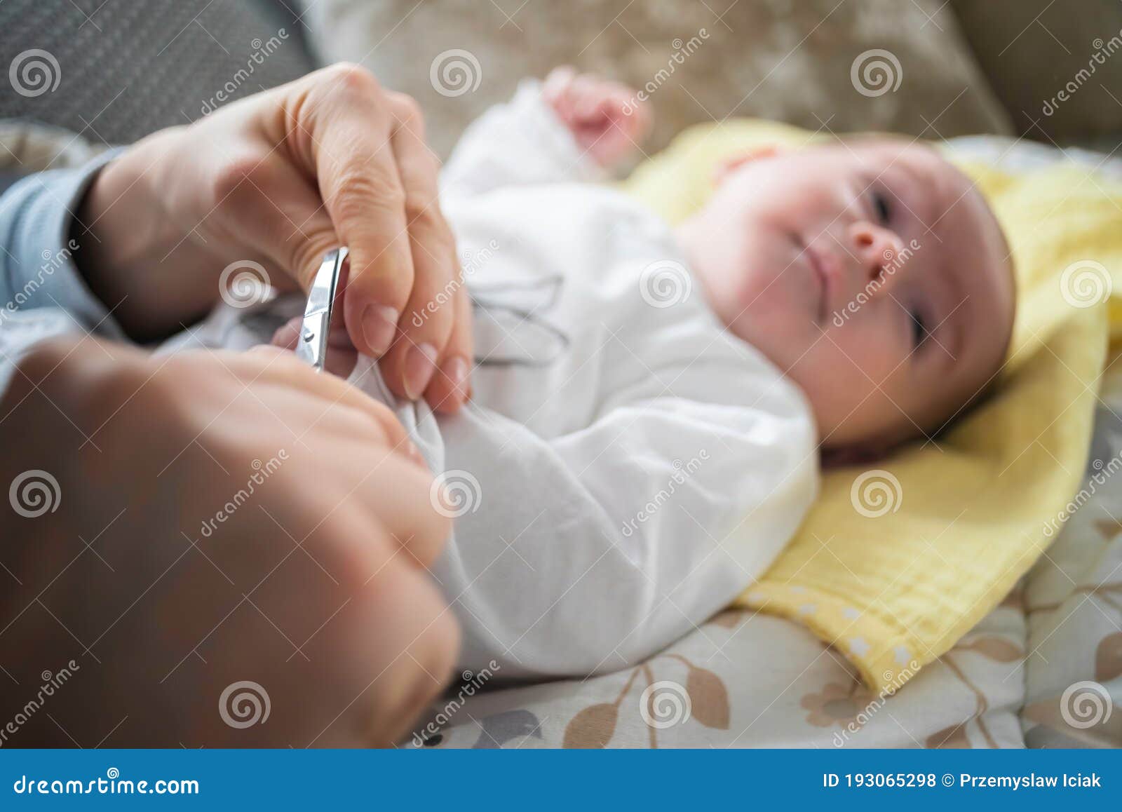 mother trimming newborns nails on a bed