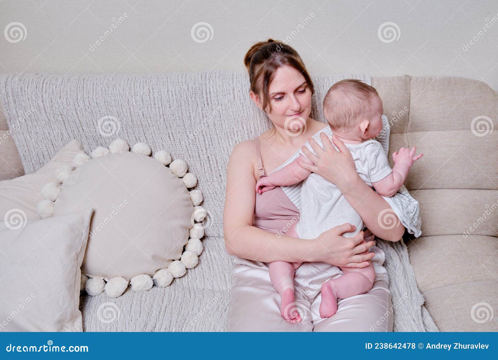 a mother woman holds an infant baby to regurgitate excess air after breastfeeding. mom with a child boy holds vertically after