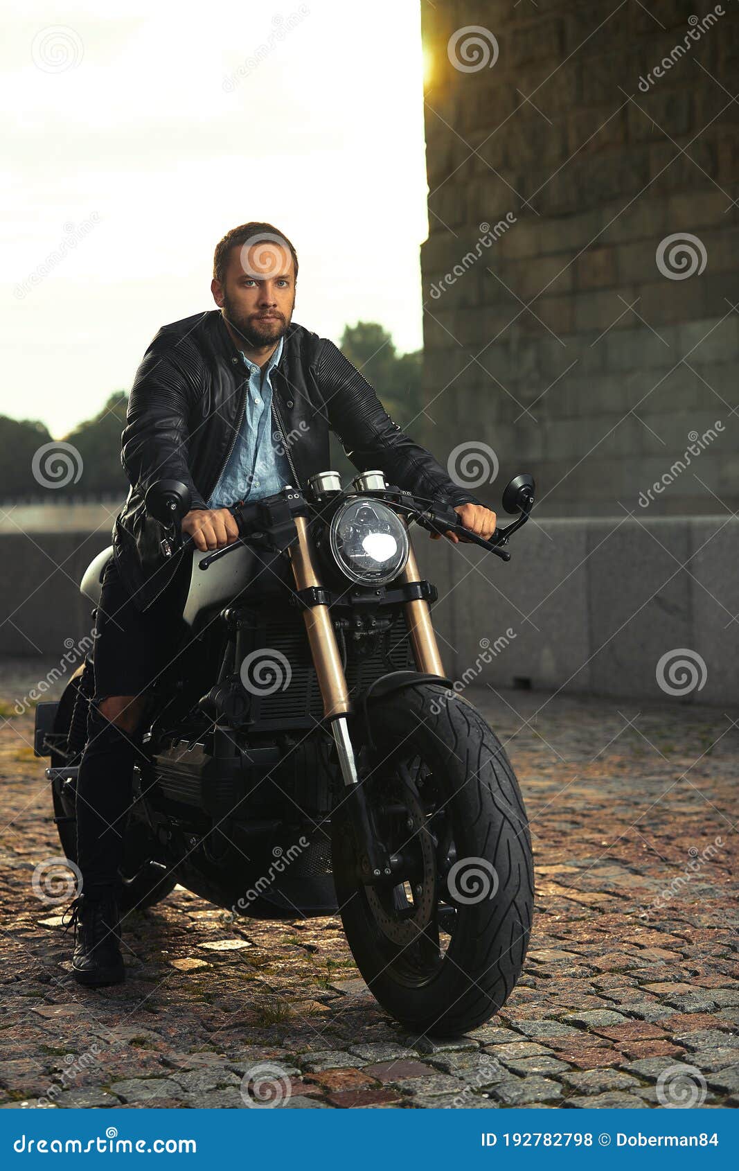 Hombre joven con estilo en chaqueta de cuero sentado en moto