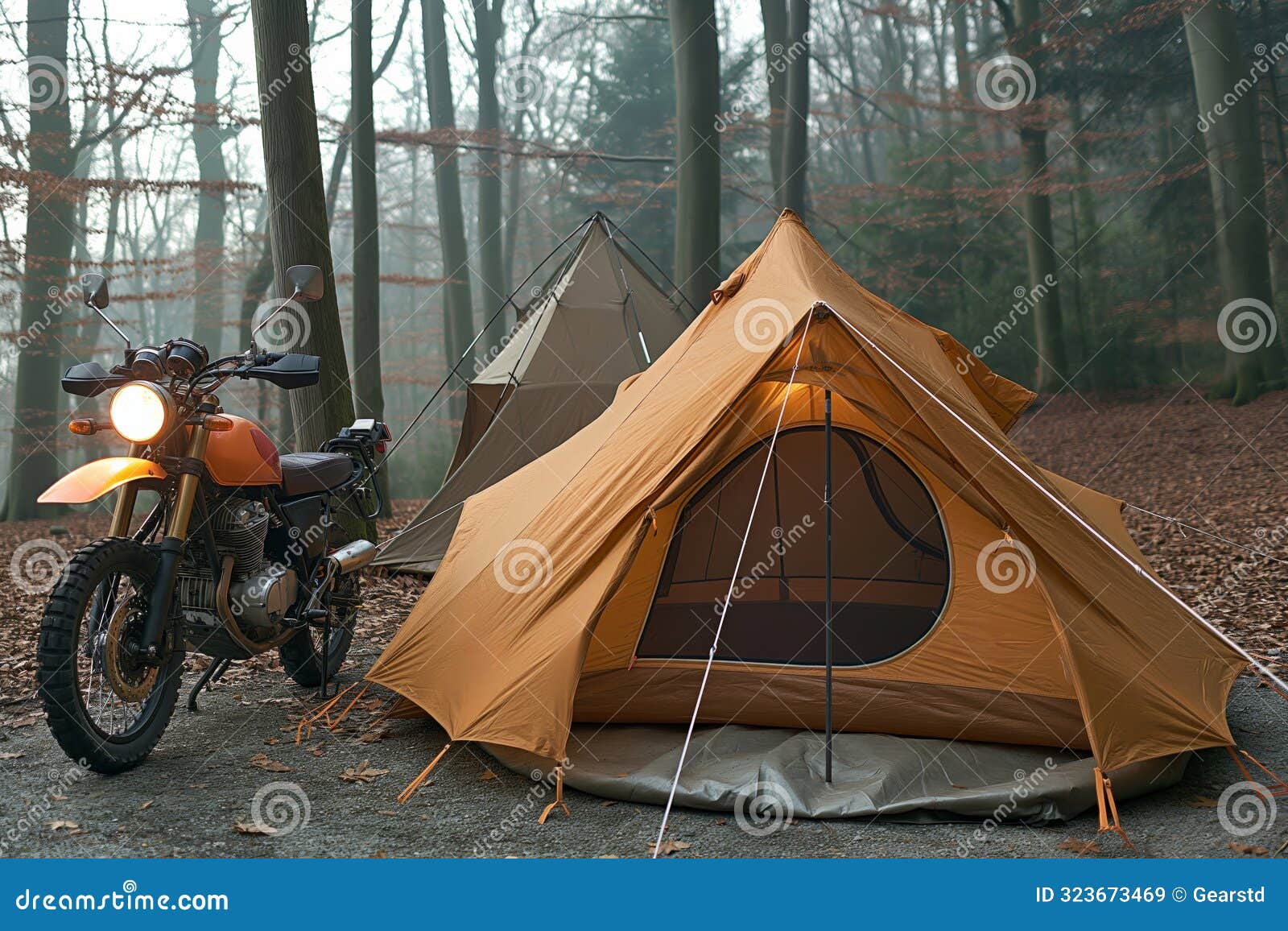 motorcycle by tents in forest, ready for adventure trip.