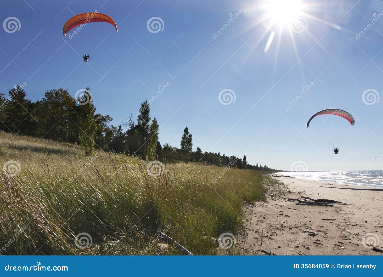 motorized hang glider kites flying over secluded beach