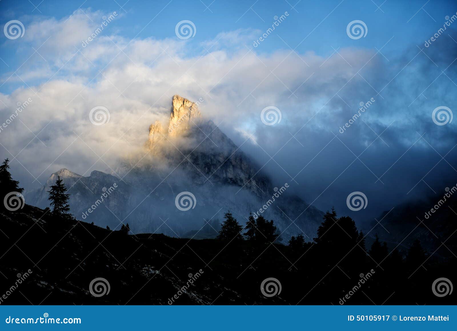 mount sass de stria at sunrise, blue sky with clouds and fog, falzarego pass, dolomites, veneto, italy