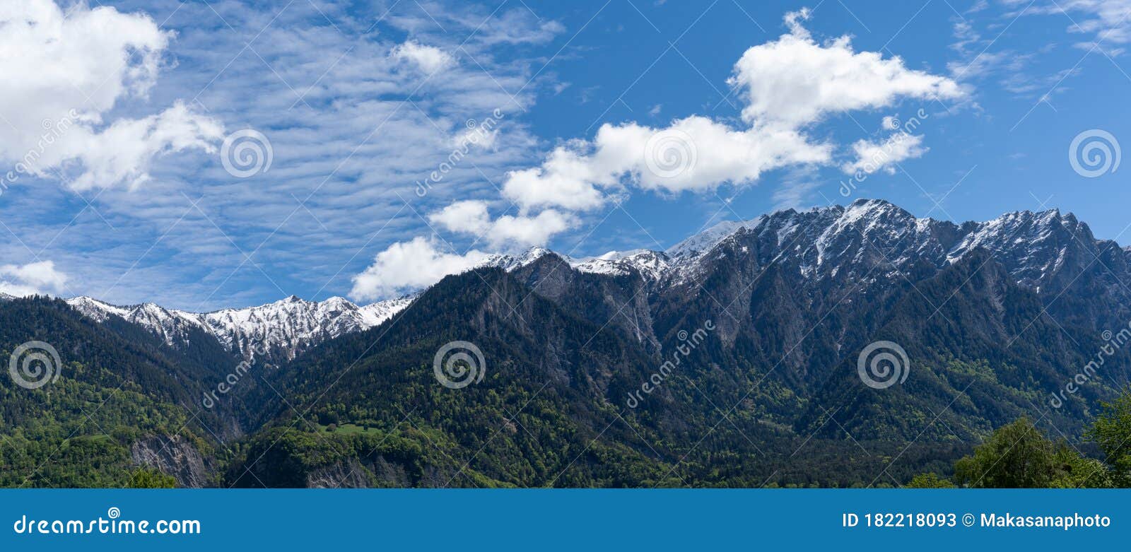 Mountain Landscape With Jagged Snow Covered Peaks And Green Forest