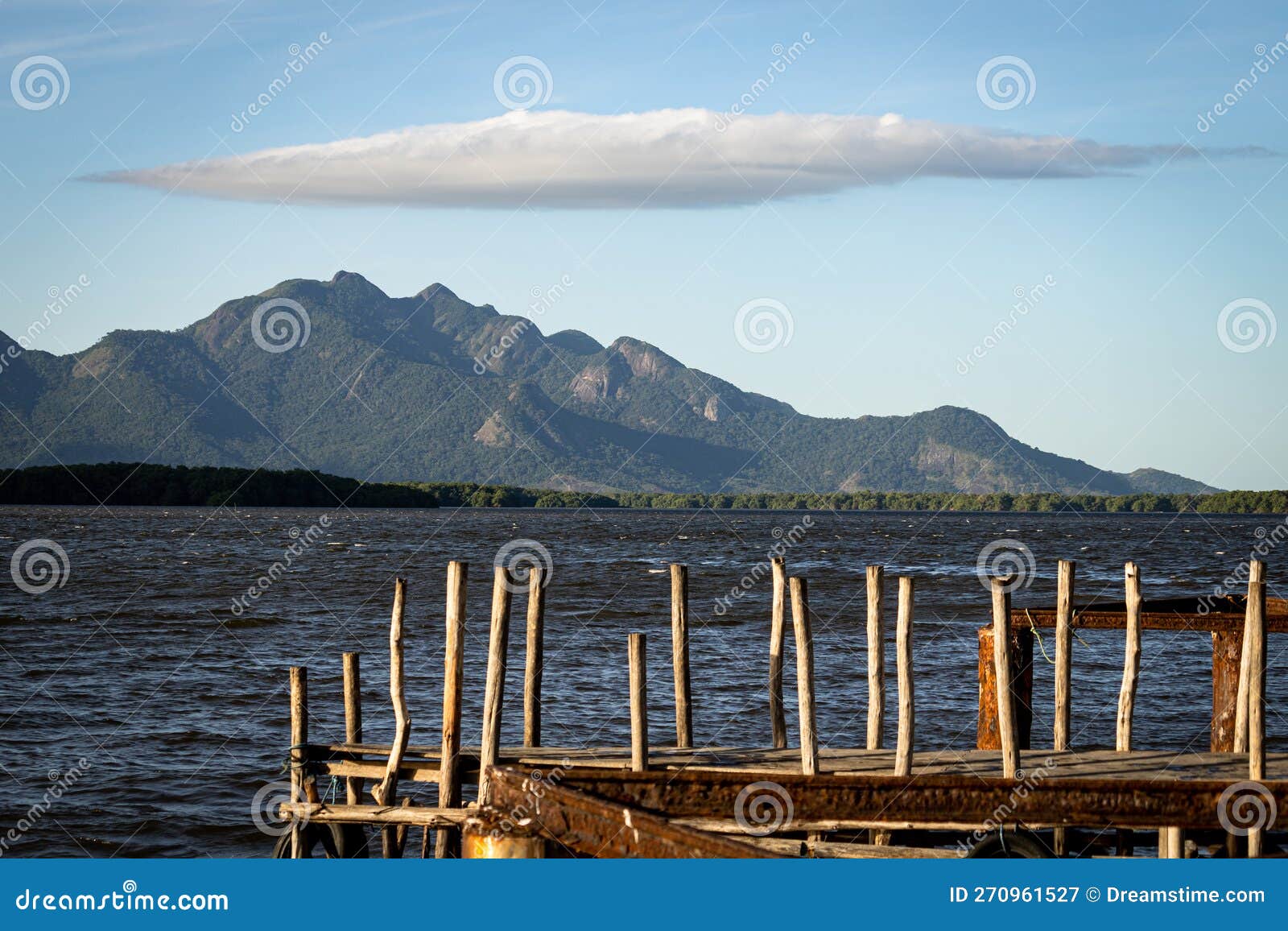 mountain of mestre alvaro with cloud in the  of an umbrella, wooden pier in the foreground
