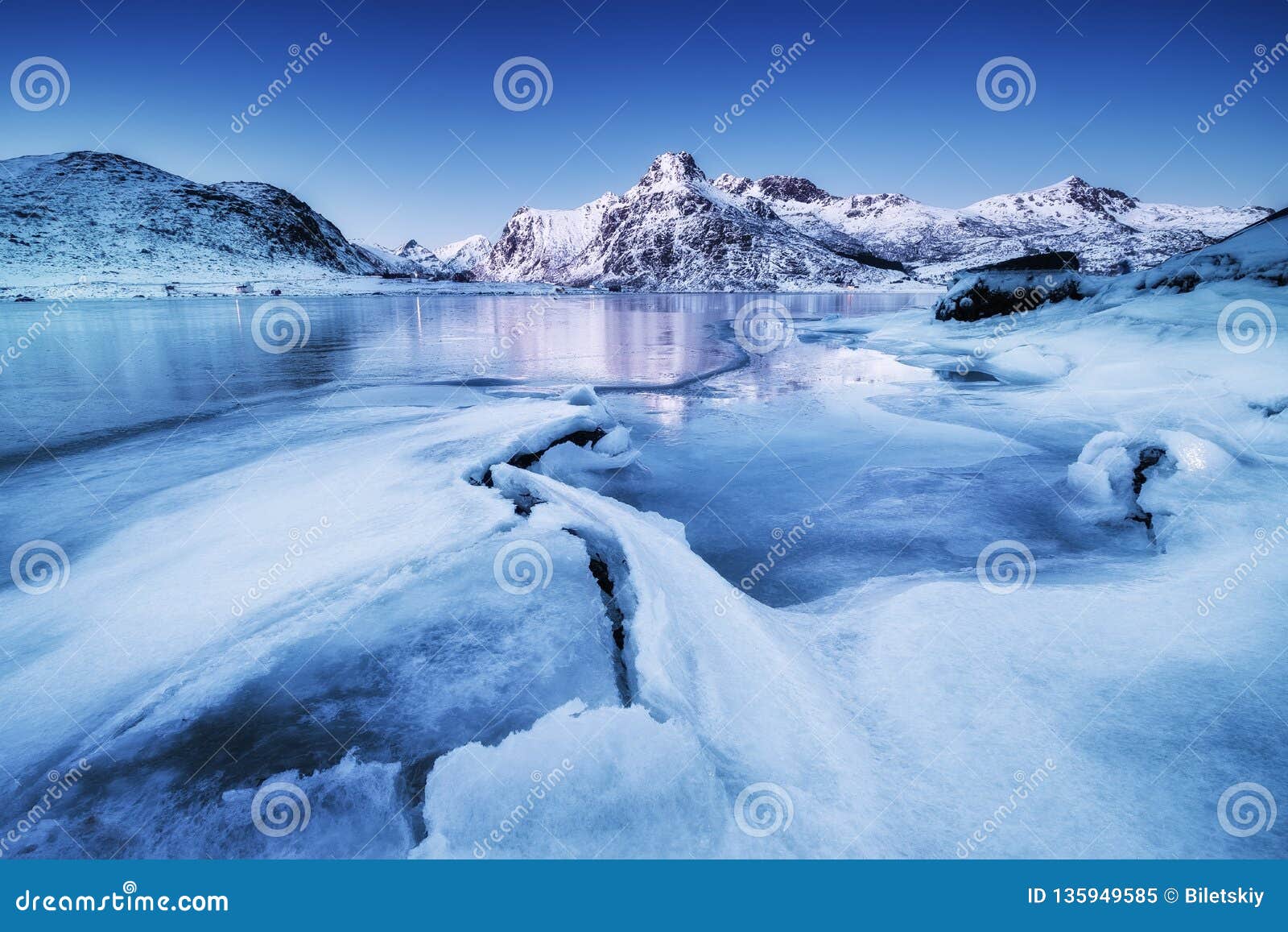 mountain ridge and ice on the frozen lake surface. natural landscape on the lofoten islands, norway.