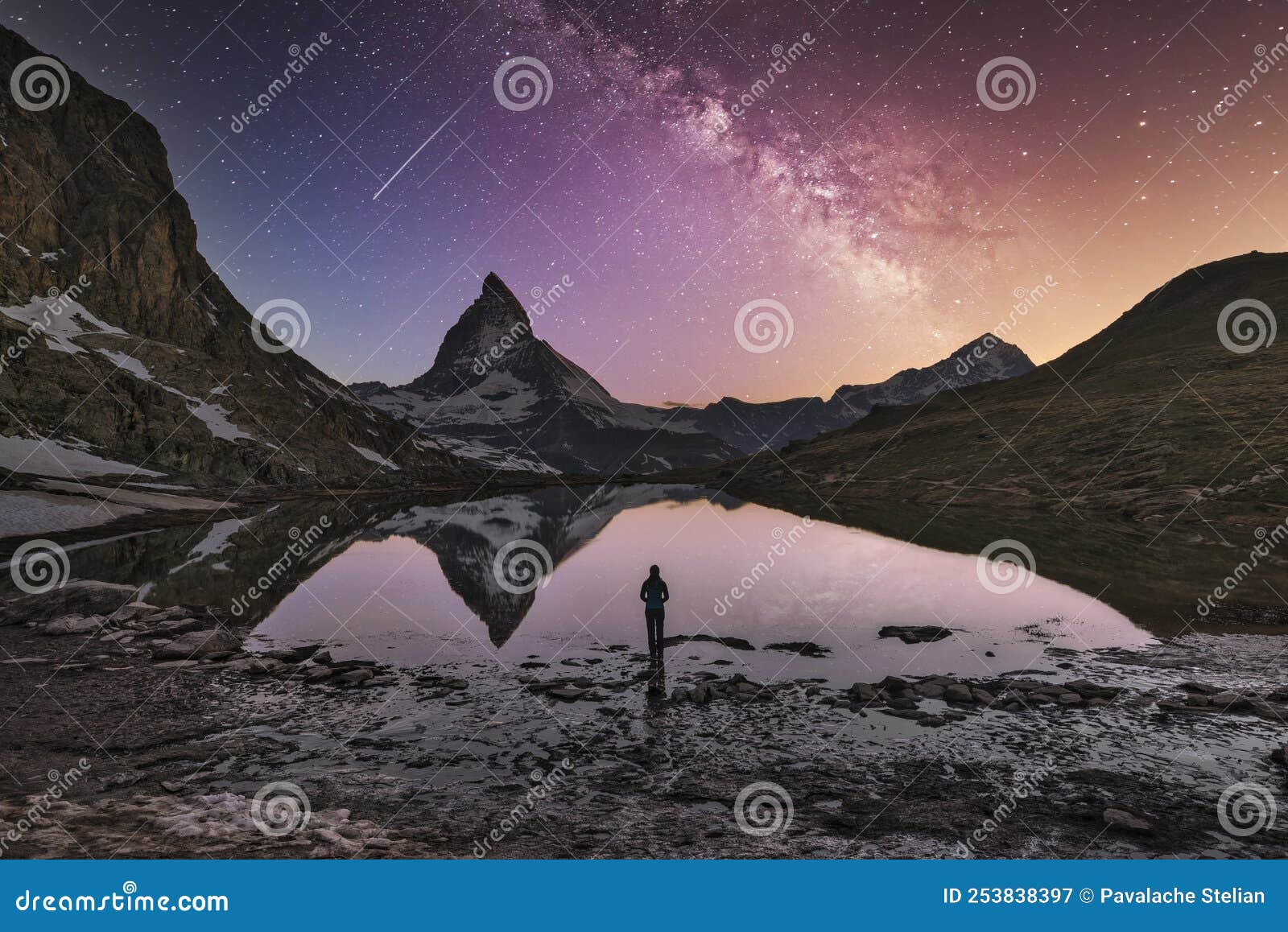mountaineer stands in front of the lake where milky way galaxy, matterhorn 4478m and dente blanche 4357m reflected in the riffelse