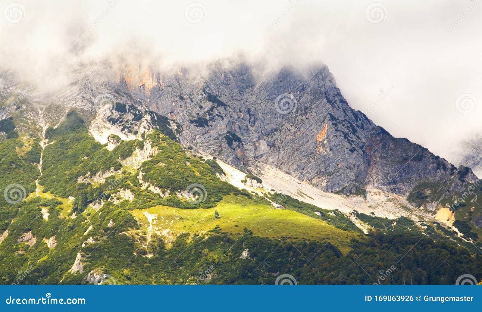mountains in the alps with cloudy hillsides, alp and chalet