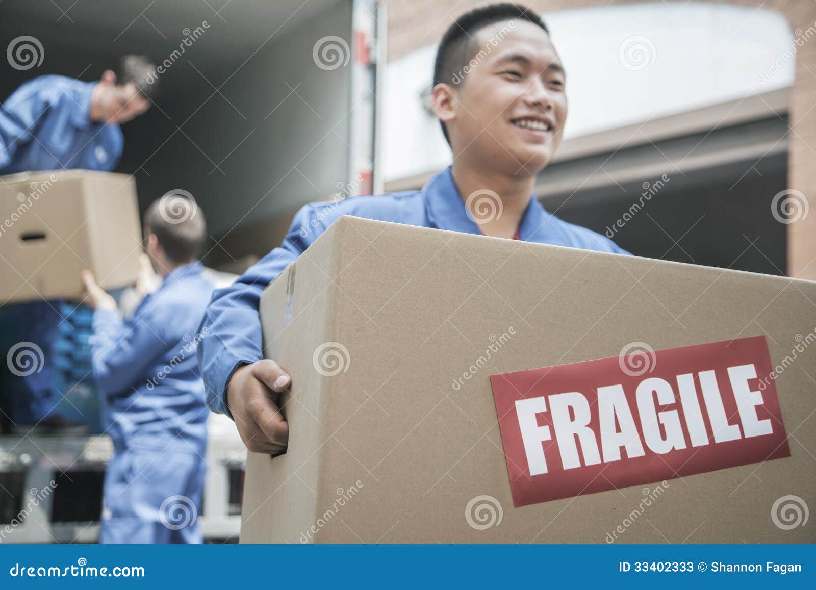 Movers Unloading a Moving Van and Carrying a Fragile Box Stock Image