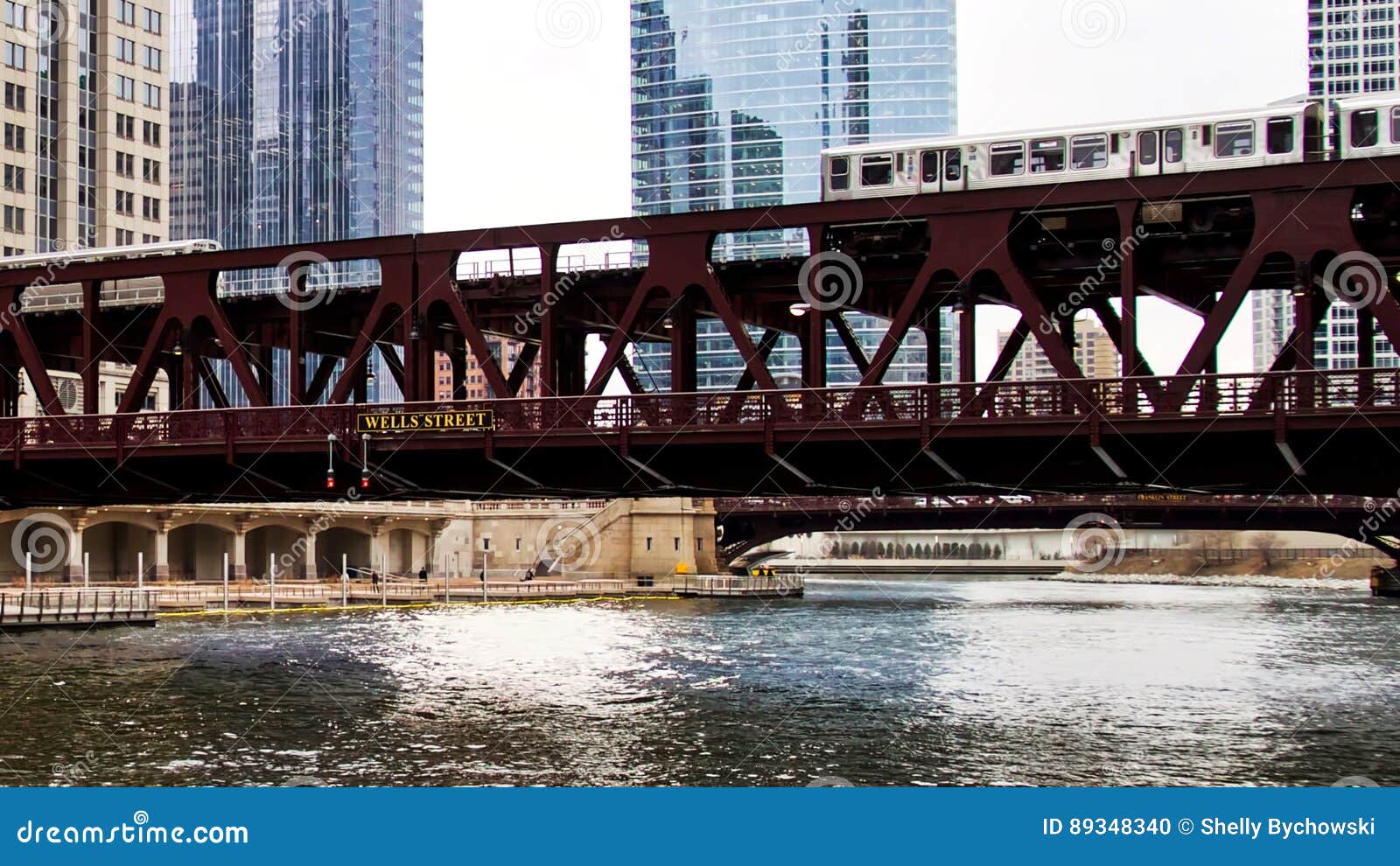 moving brown line elevated el train, part of chicago`s iconic transit system, passing over chicago river at wells street