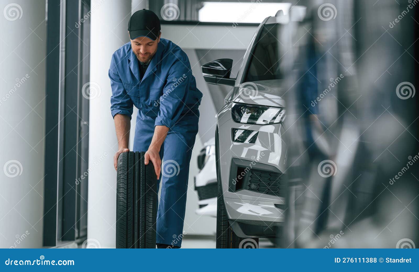 Moving the Tire. Man in Blue Uniform is Working in the Car Service