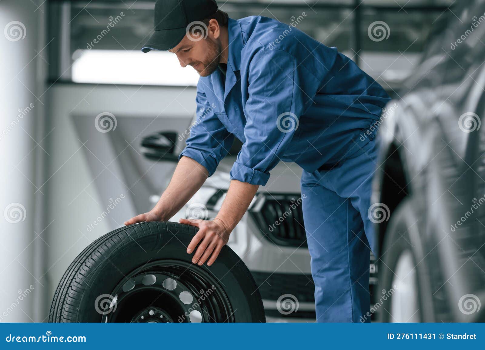 Moving the Tire. Man in Blue Uniform is Working in the Car Service