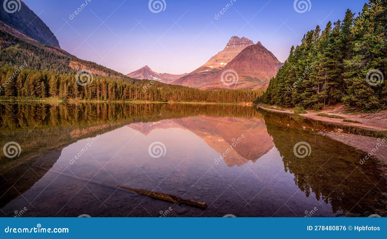 mt. wilbur reflection in the smooth surface of fishercap lake at sunrise in glacier national park