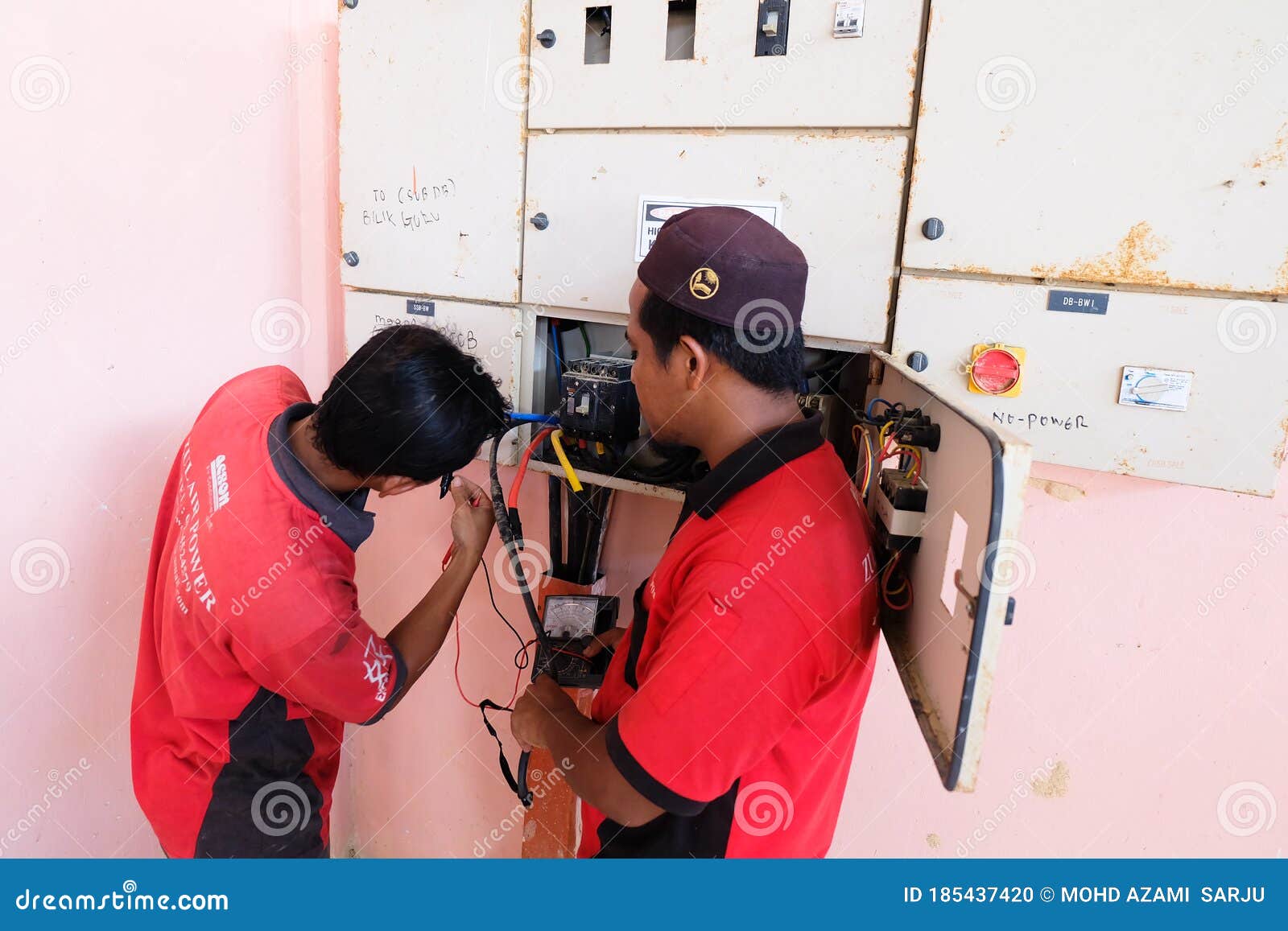 Technician Wiring Cable in Front of Electrical Panel for Control and