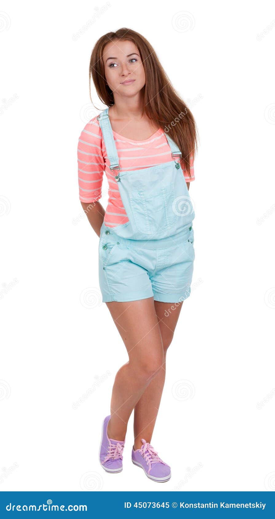 Muchacha adolescente pelirroja en pantalones cortos Aislado en el fondo blanco la muchacha atlética sonríe enigmáticamente mirando al lado