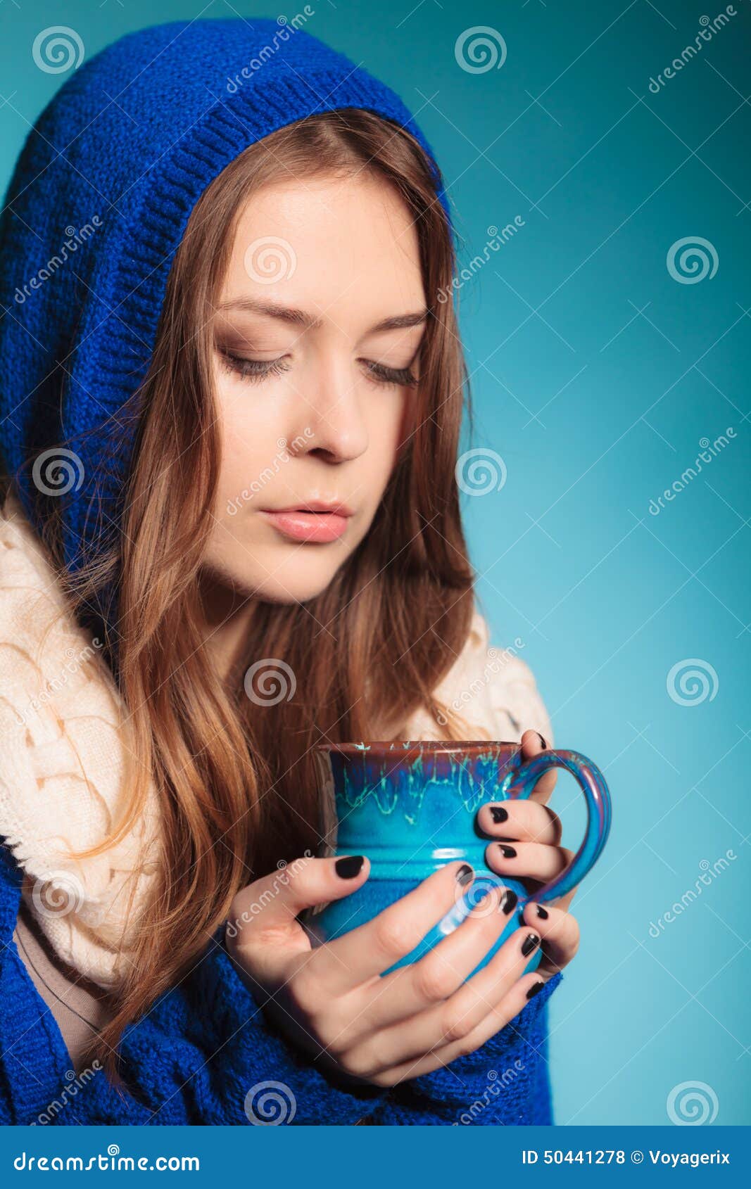 Muchacha adolescente que sostiene la taza azul con la bebida caliente. Bebida caliente Muchacha adolescente del primer que sostiene la taza azul con té o café de la bebida Mujer que se calienta