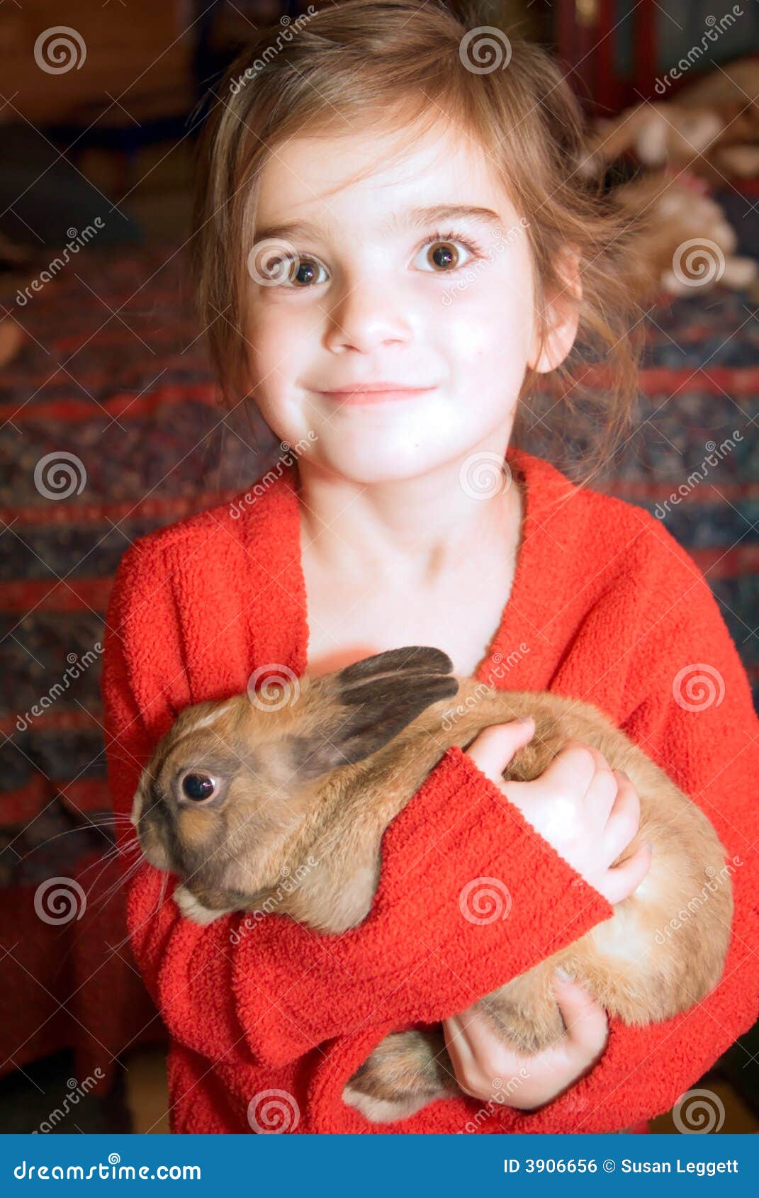 Muchacha Brown-eyed con el conejo. ¡Creo que ella está absolutamente contenta con se para poder sostener este conejo!