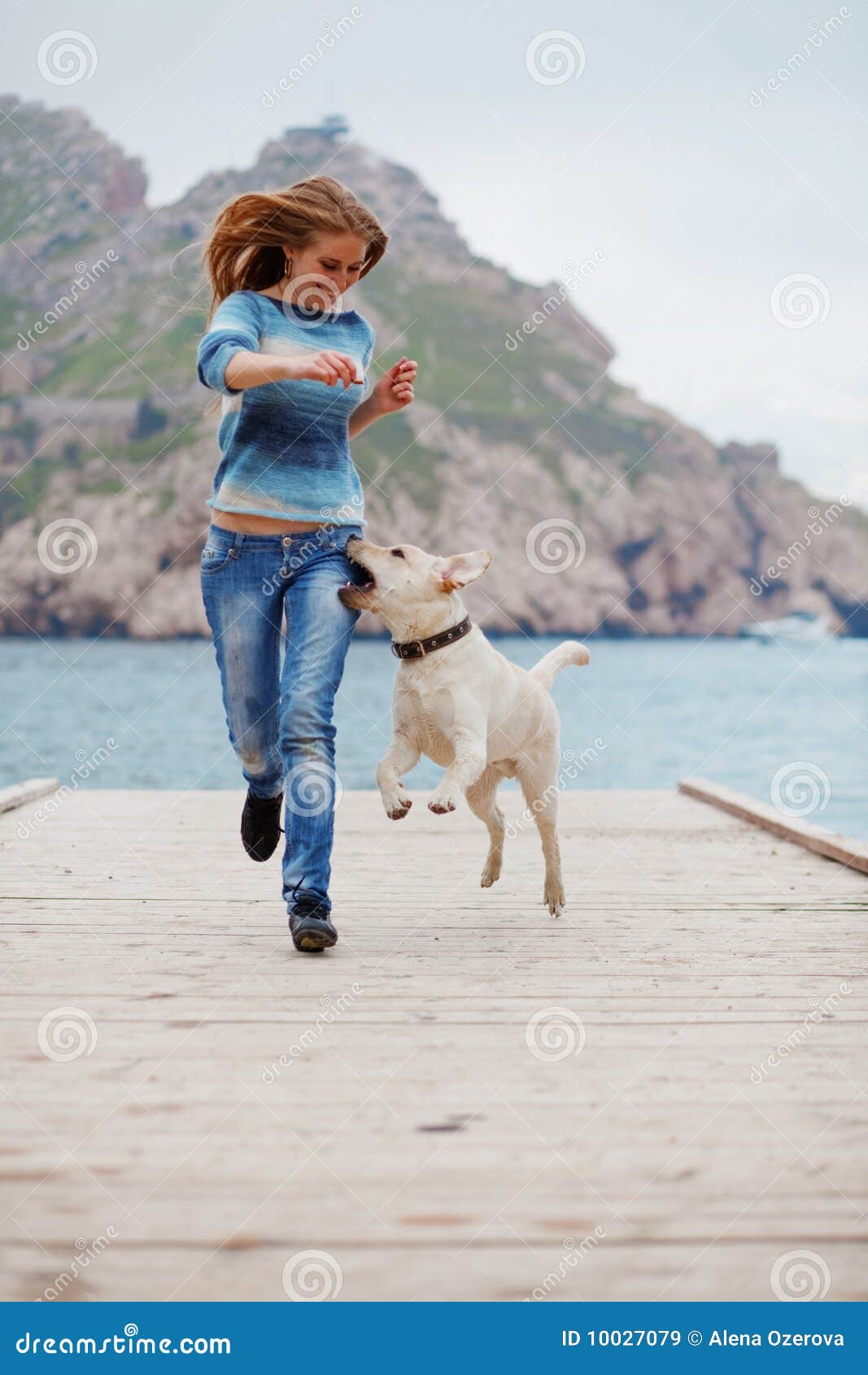 Muchacha con el funcionamiento del perro. Muchacha hermosa que juega con su perro en litera cerca del mar