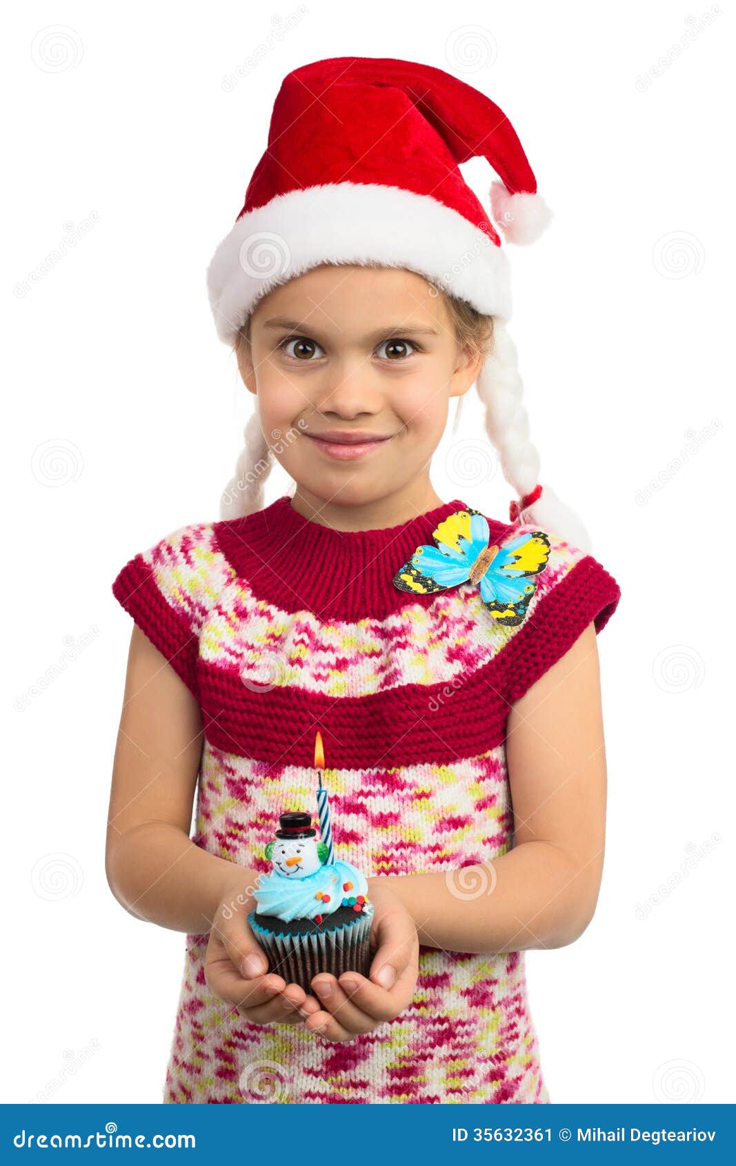 Muchacha con la magdalena del día de fiesta. La chica joven hermosa en el sombrero de Papá Noel y una mariposa en su hombro sostiene la magdalena colorida con el muñeco de nieve del juguete encima de él, aislado