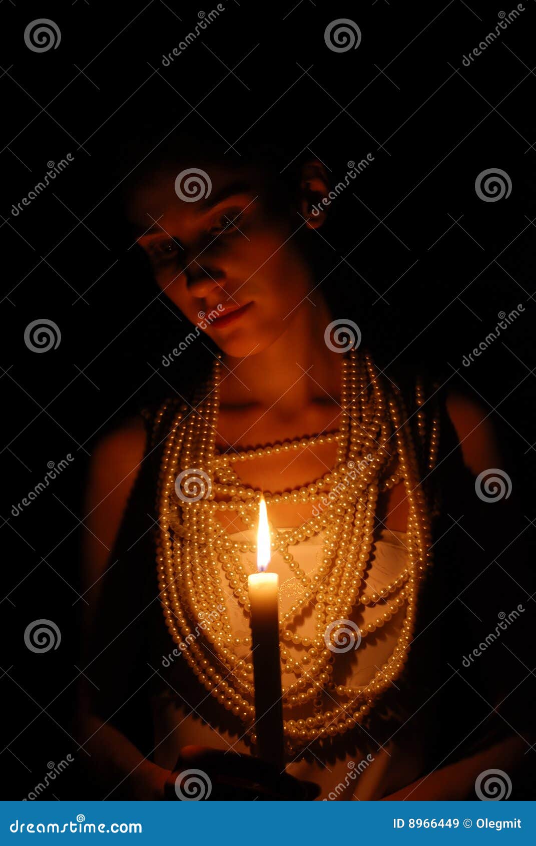 Muchacha con la vela ardiente en oscuridad. Muchacha con el collar ardiente de la vela y de la perla en la obscuridad