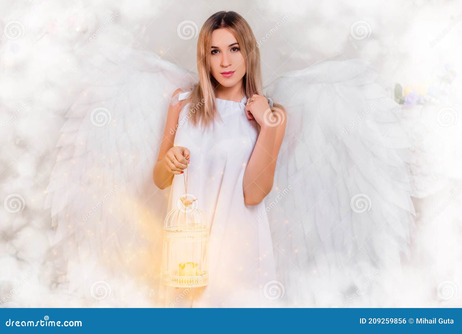 Muchacha Con Una Túnica Blanca Con Grandes Alas Blancas Detrás De Su  Espalda Se Para En Nubes Blancas Y Sostiene Una Lámpara Foto de archivo -  Imagen de traje, encantador: 209259856