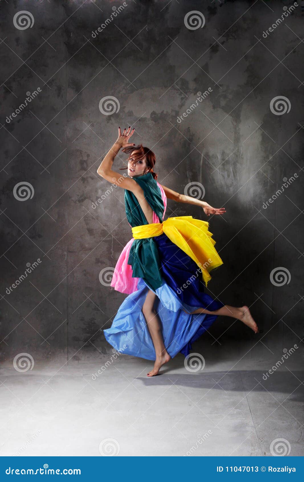 Muchacha de baile moderna joven en alineada colorida en el fondo gris del estudio del grunge sucio