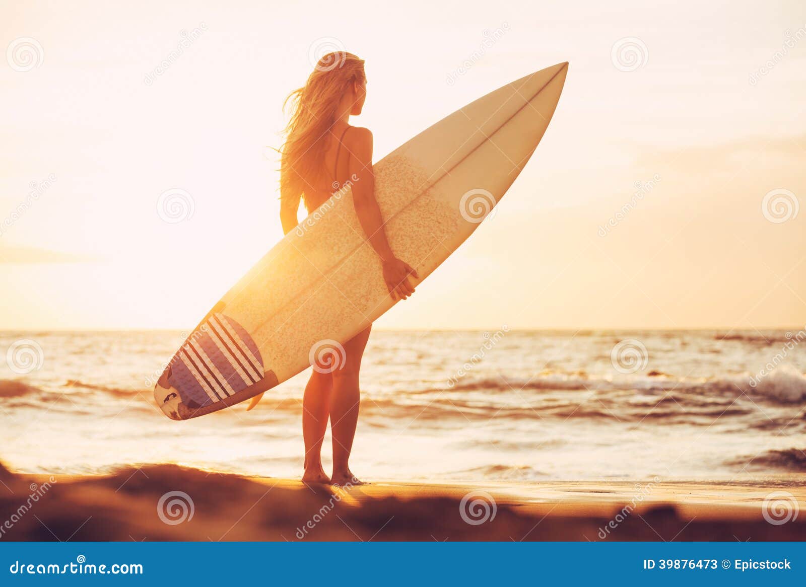 Muchacha de la persona que practica surf en la playa en la puesta del sol. Muchacha atractiva hermosa de la persona que practica surf en la playa en la puesta del sol