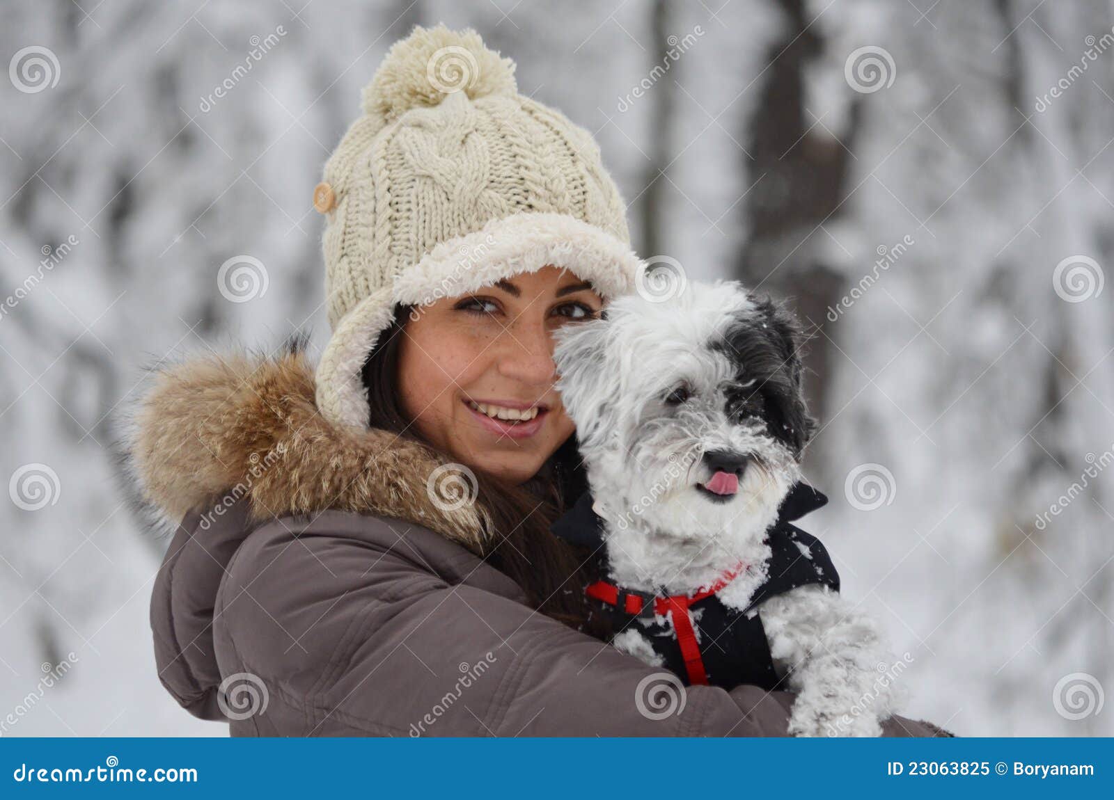 Muchacha en el bosque del invierno con su perro. Retrato de una muchacha hermosa con el sombrero en el bosque del invierno
