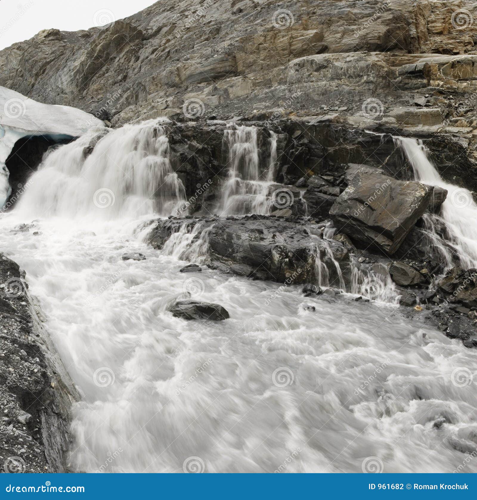 Muddy River with Waterfall Flowing from Below the Glacier Stock Photo