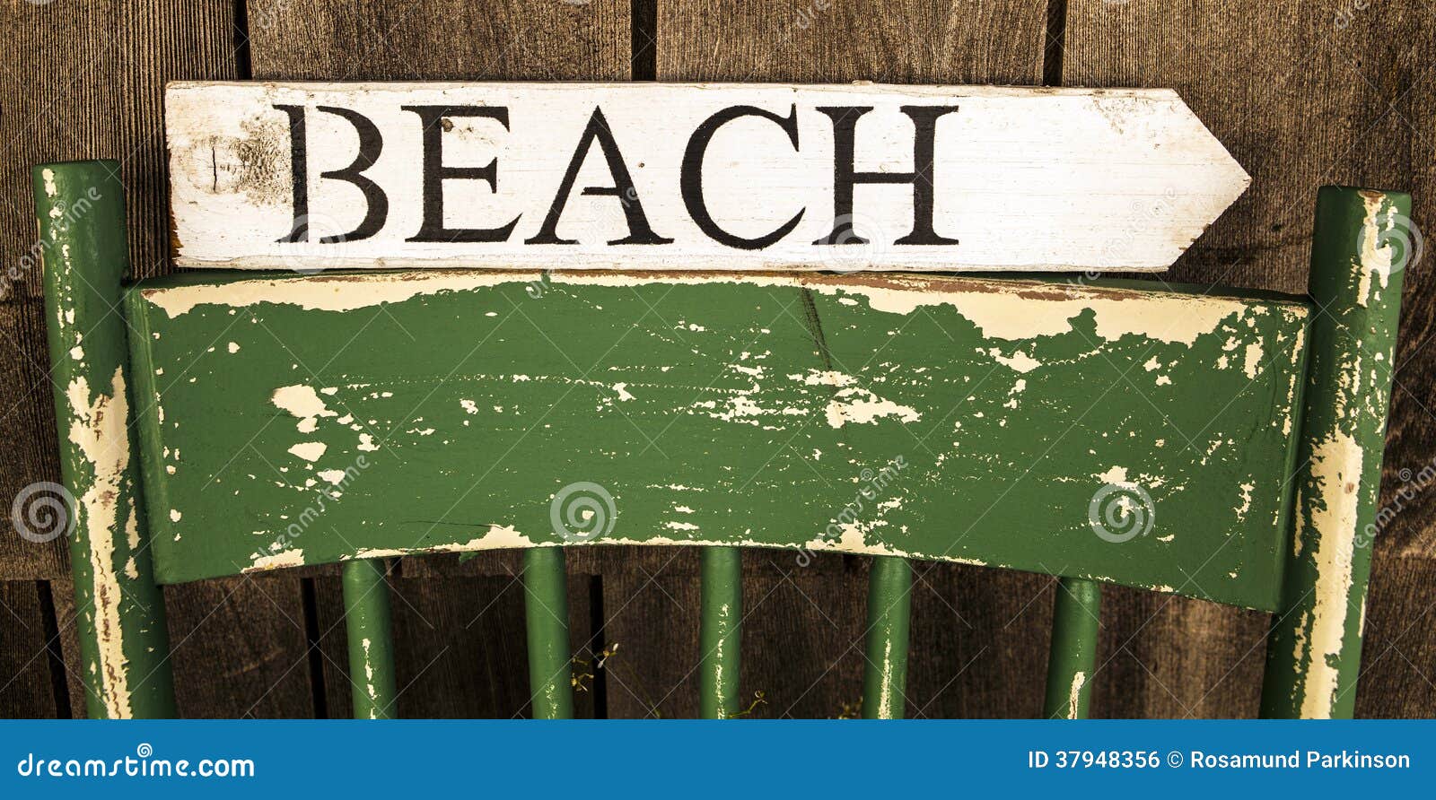 Muestra de la playa. Vare escrito en la flecha direccional de madera que se sienta encendido detrás de silla apenada