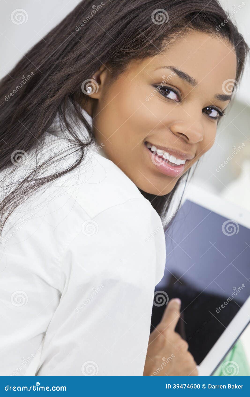Mujer afroamericana que usa la tableta. Mujer o muchacha afroamericana joven feliz hermosa que sonríe y que usa una tableta