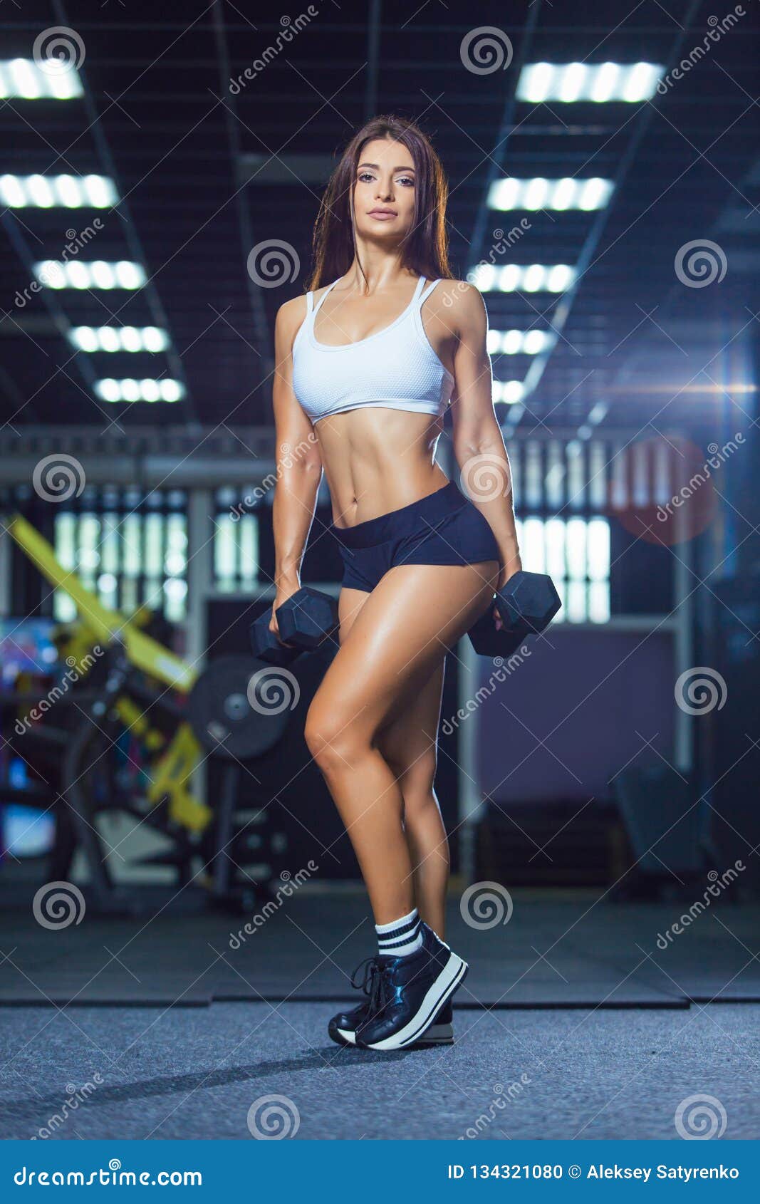 La mujer sonriente joven de los deportes felices hace ejercicios del deporte