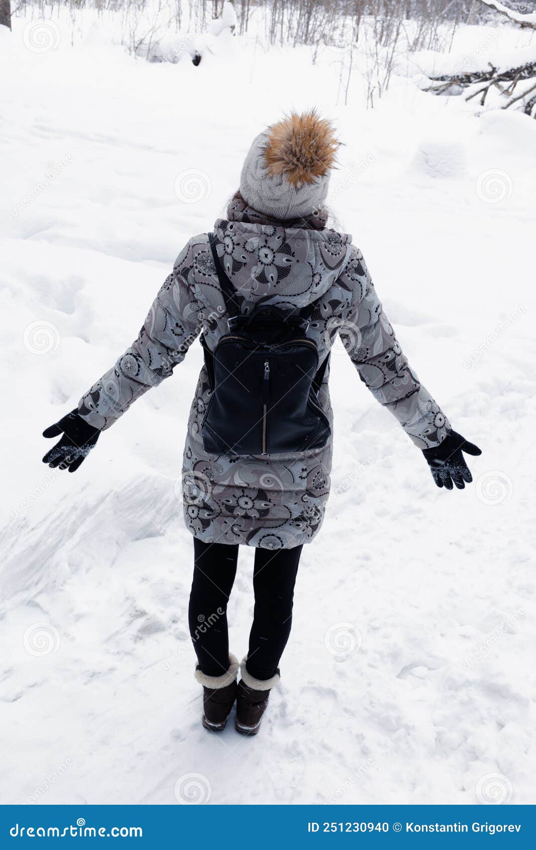 Feliz mujer joven en ropa de invierno de pie en el bosque