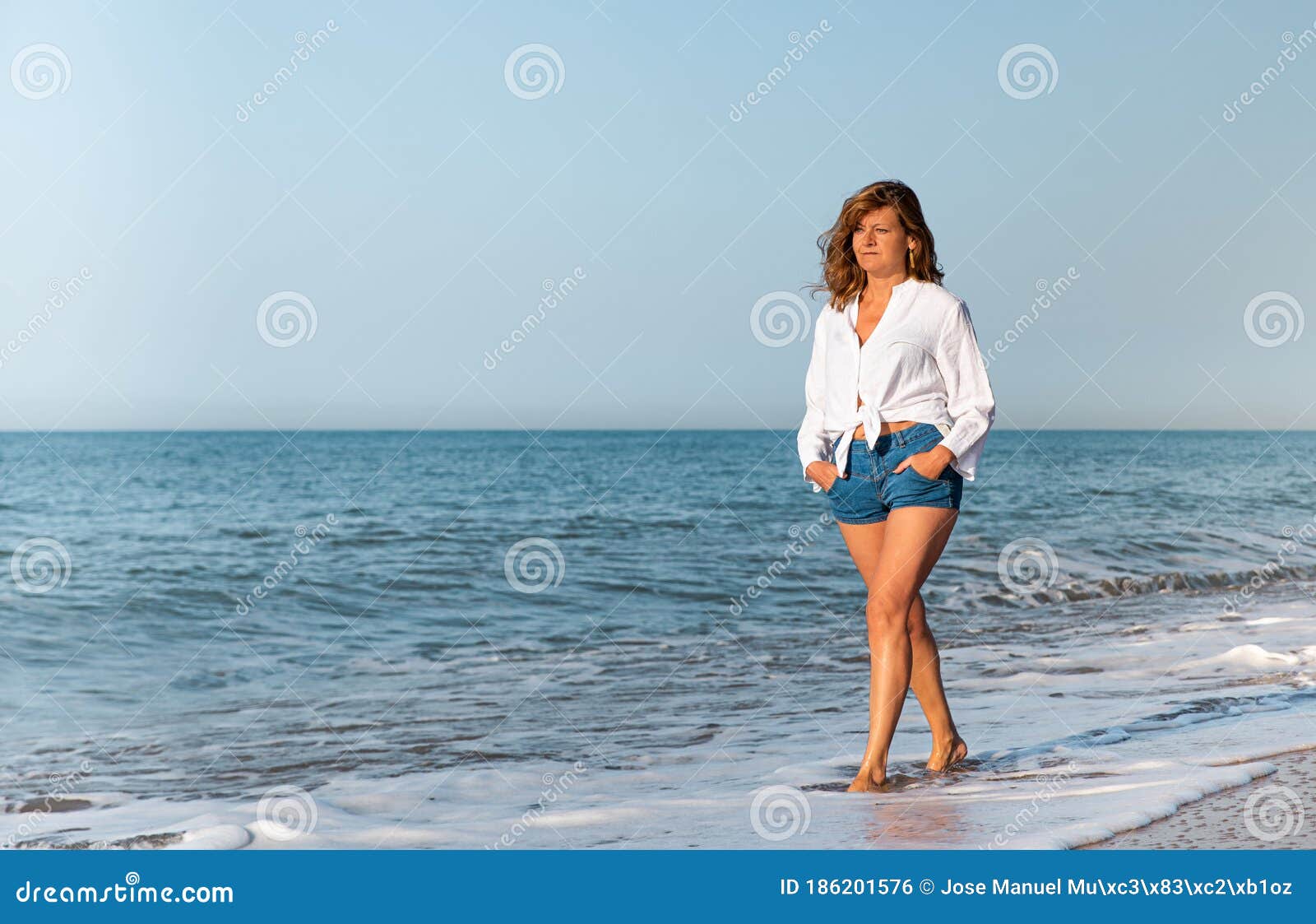 Mujer Caminando En La Playa Con Una Blanca Y Pantalones Cortos De Jean. Concepto De Vacaciones archivo - Imagen de entrar, relaje: 186201576