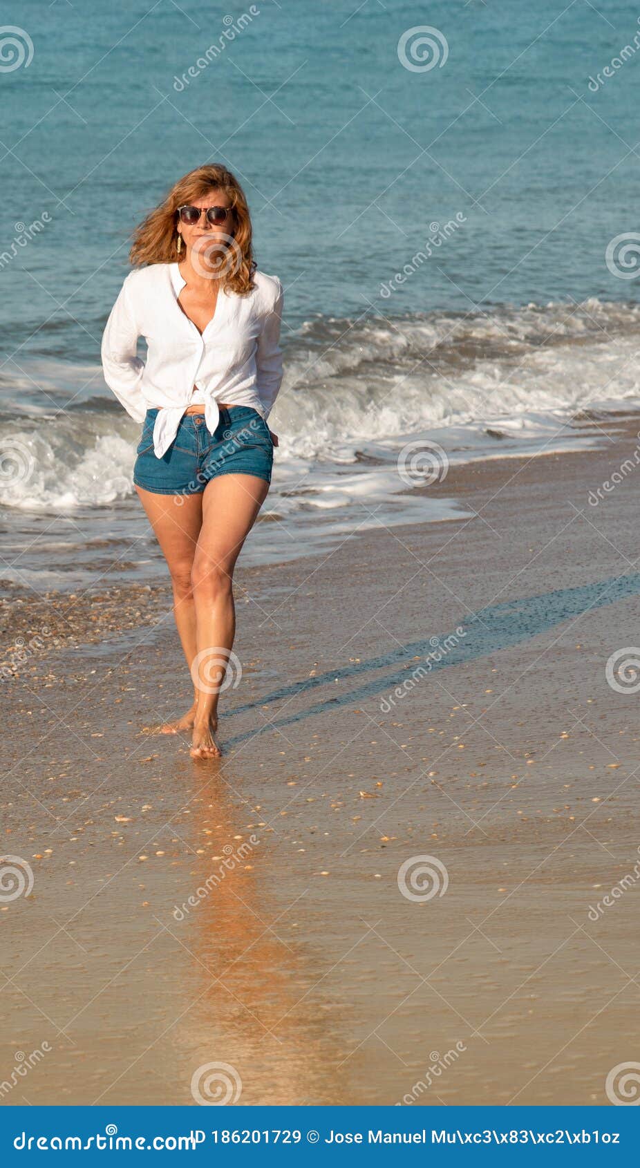 Mujer Caminando En La Playa Con Una Camisa Blanca Y Pantalones Cortos De Jean. Concepto De Vacaciones Imagen de - Imagen de edad, 186201729