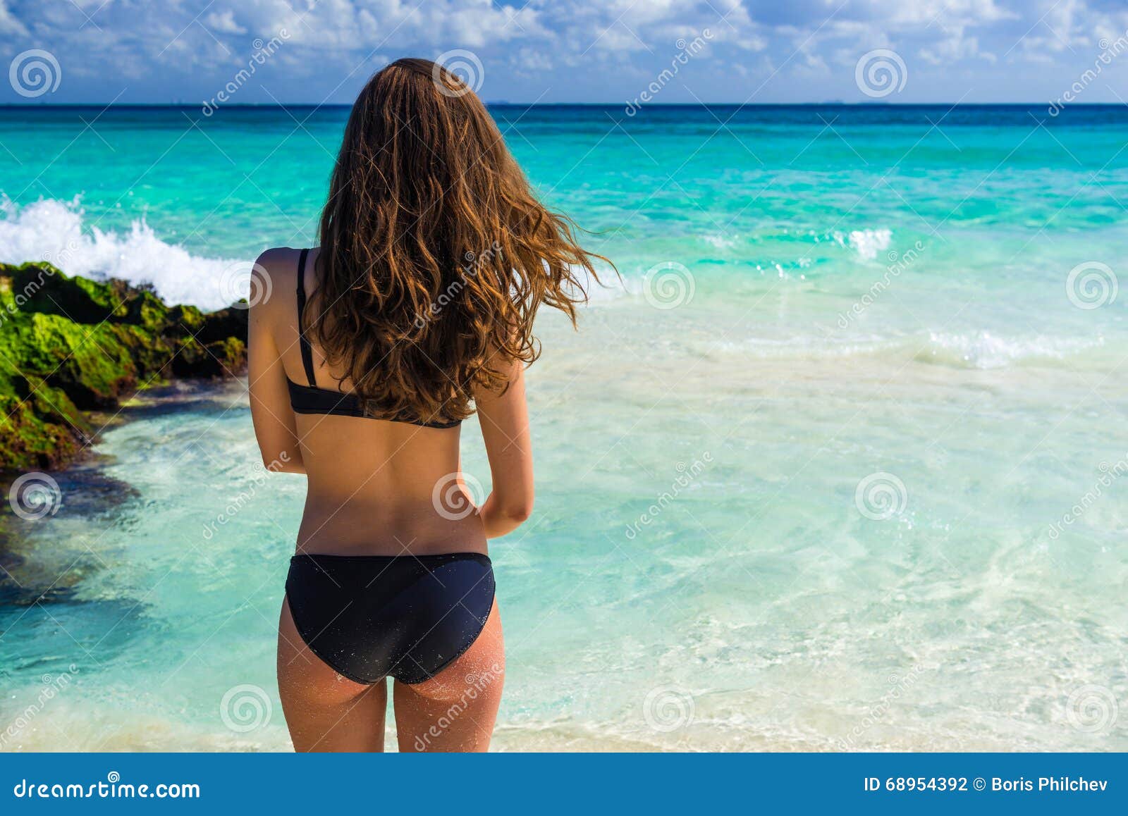 Mujer caucásica joven atractiva en el traje de baño negro que mira en el SE. Mujer caucásica joven atractiva en el traje de baño negro que mira en el mar la playa tropical