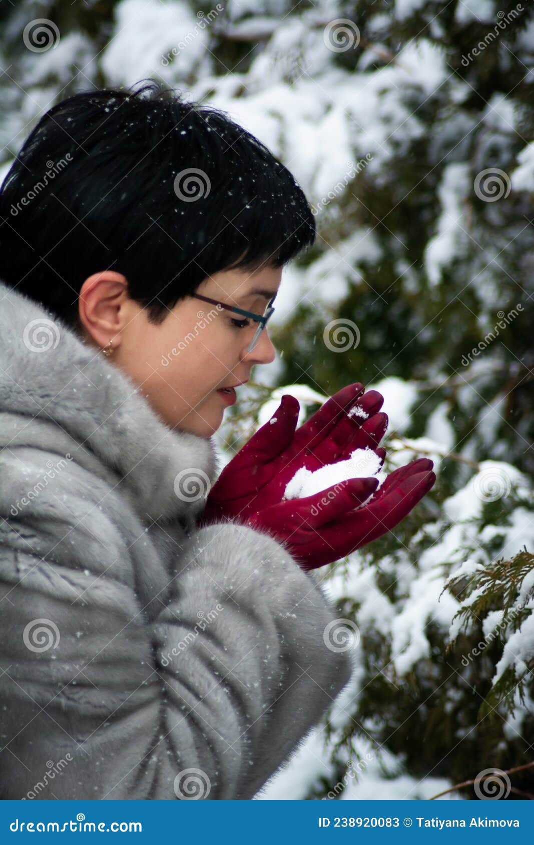 Mujer Con Abrigo De Piel Gris Con Guantes Rojos Sostiene Nieve En Las  Manos. Contra El Fondo De Los Abetos Cubiertos De Nieve. Imagen de archivo  - Imagen de exterior, lifestyle: 238920083