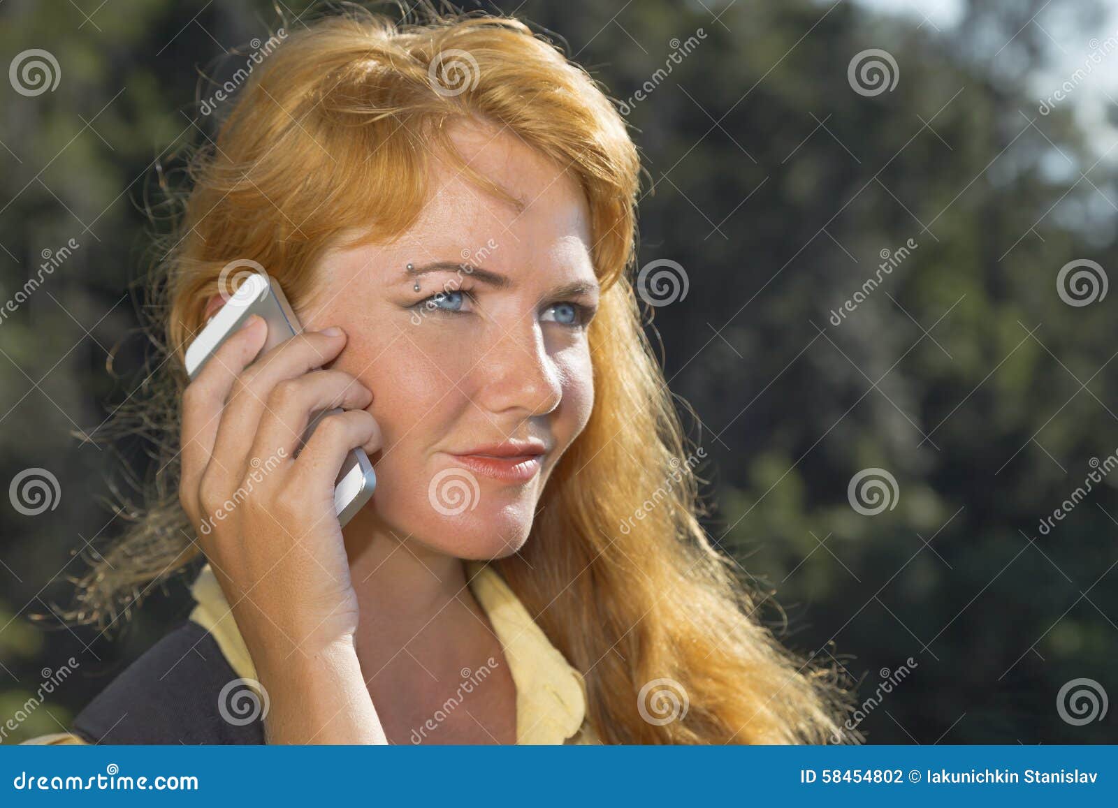 Mujer con el teléfono. Muchacha pelirroja hermosa que habla en el teléfono en las montañas