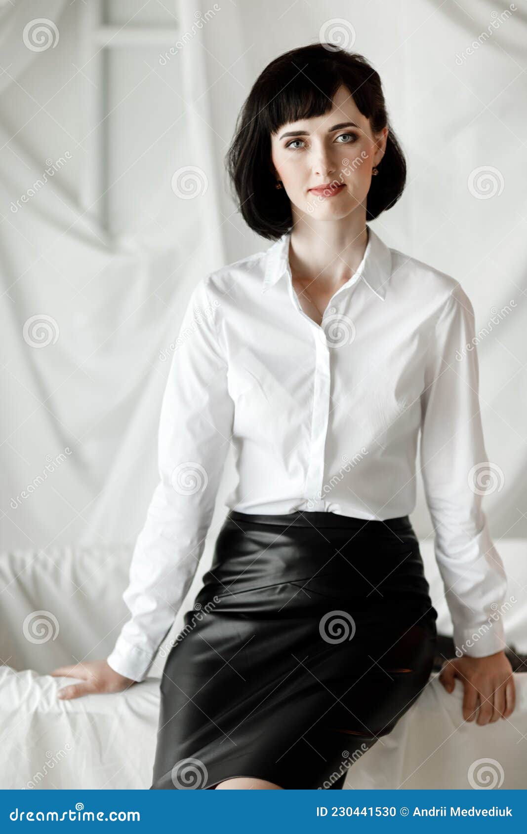 Mujer De Negocios Segura Y Atractiva. Chica Con Camisa Blanca Y Falda De Cuero Sentada En La Oficina De La Foto archivo - Imagen de morena: 230441530