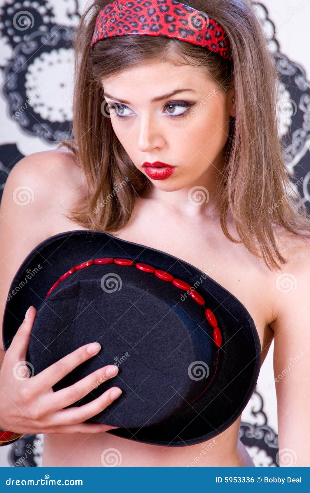 Mujer del sombrero superior. Mujer joven hermosa con las tetas al aire en su dormitorio que cubre sus pechos con un sombrero superior negro