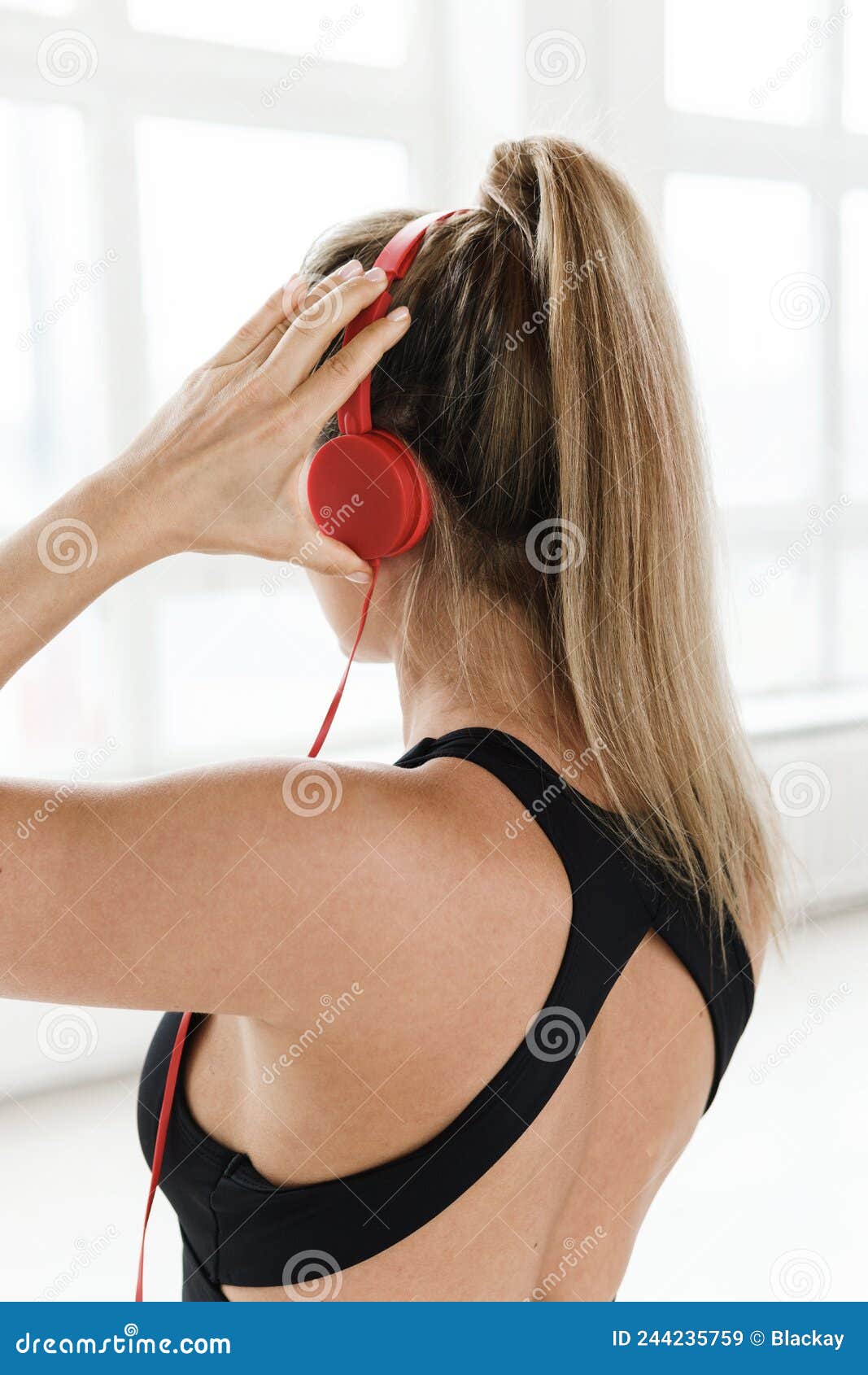 mujer deportiva con auriculares rojos escuchando música para hacer