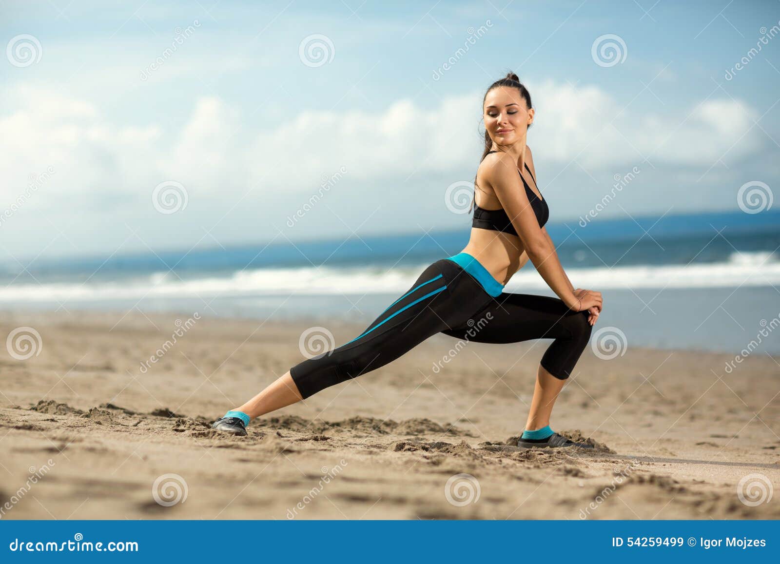 Mujer deportiva joven que hace entrenamiento en la playa hermosa