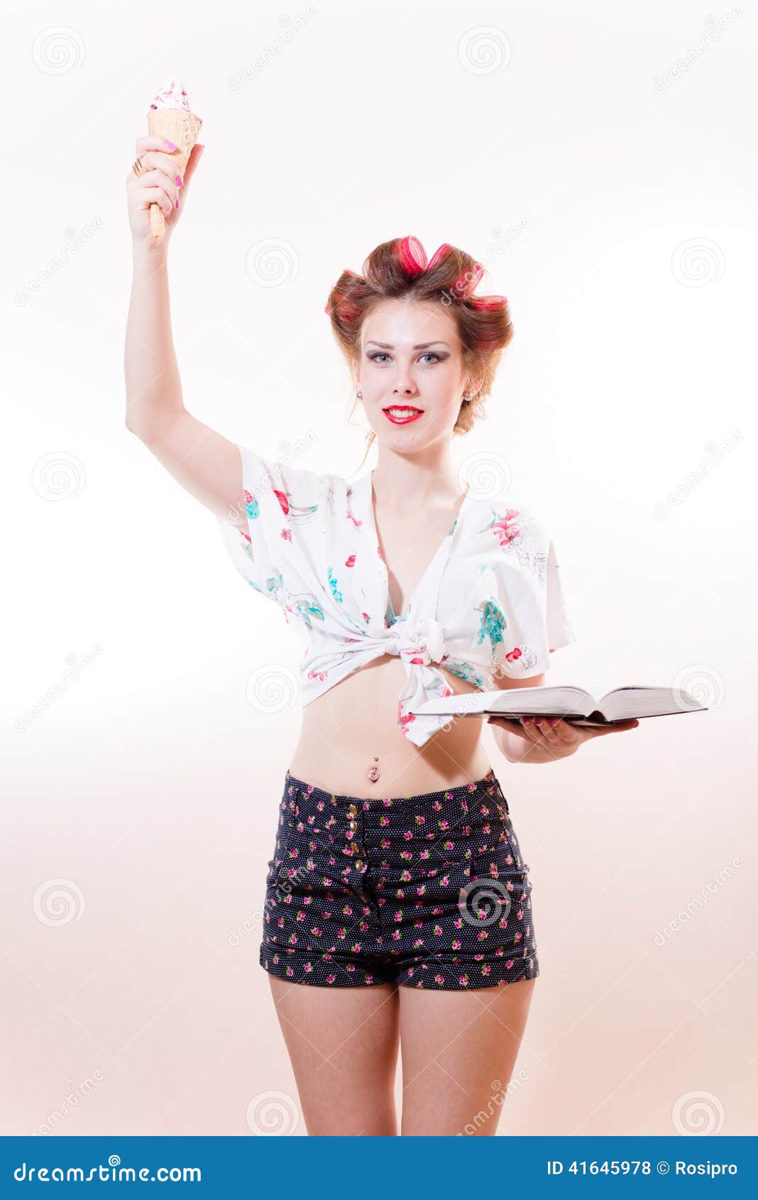 Mujer elegante joven hermosa con el helado y el libro que presentan como estatua de la libertad que mira in camera aislada en el. Muchacha bonita modela rubia atractiva asombrosa como estatua de la libertad que mira in camera aislada en la imagen blanca del retrato del fondo del espacio de la copia