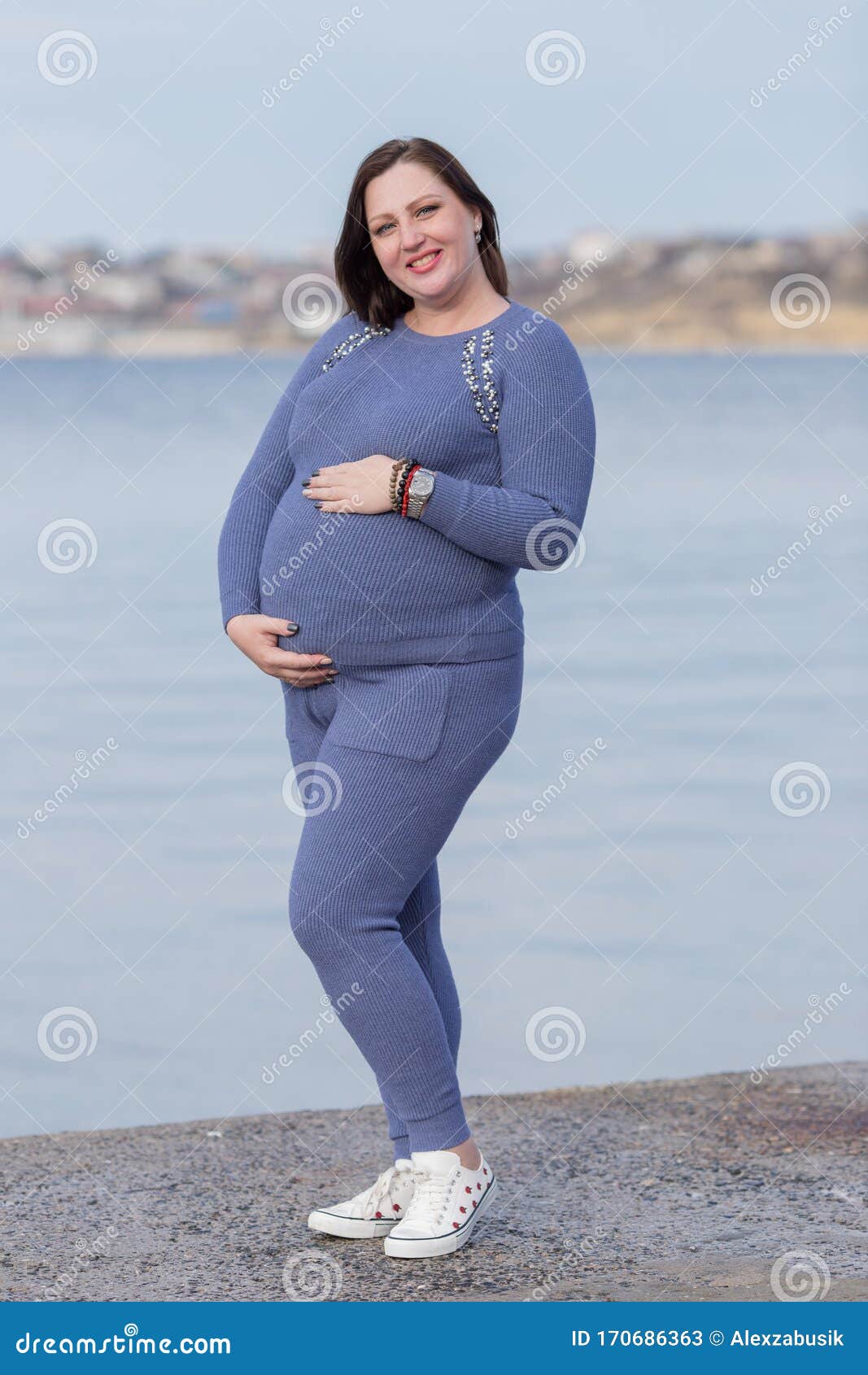 Mujer Embarazada En Ropa Deportiva Posando Con Las Manos En El Estómago Contra El Mar Imagen de archivo - de morena, longitud: 170686363