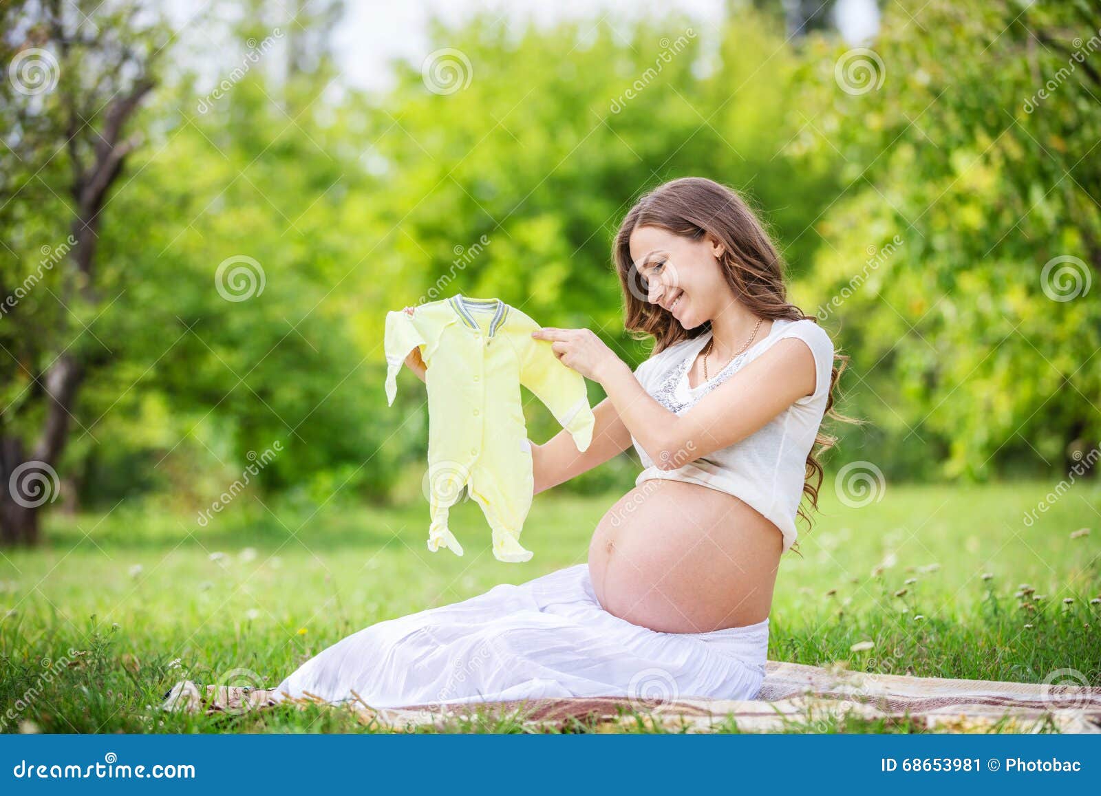 Mujer Embarazada Hermosa Que Sostiene El Mono Del Bebé Y Que Sonríe En El Parque Imagen de archivo - de verde, feliz: 68653981