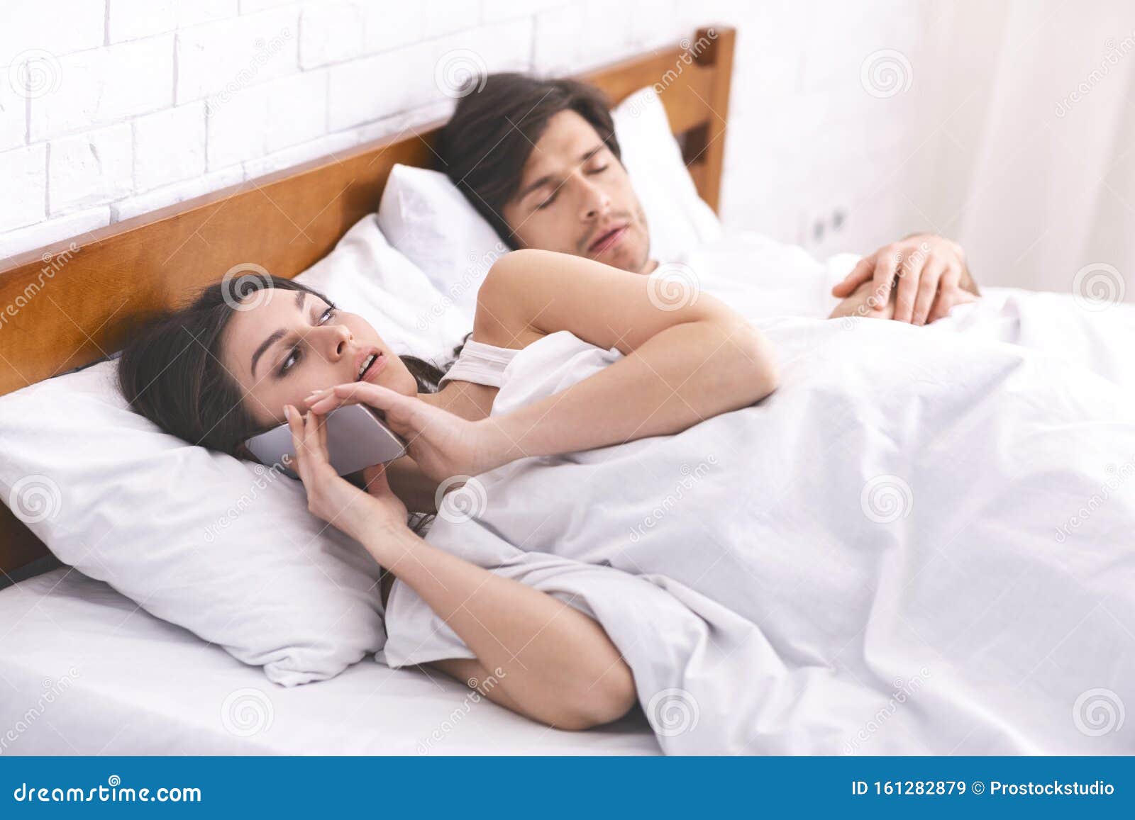 Mujer Engañando Hablando En Privado a Través Del Teléfono Celular En La Cama Familiar Imagen de archivo foto