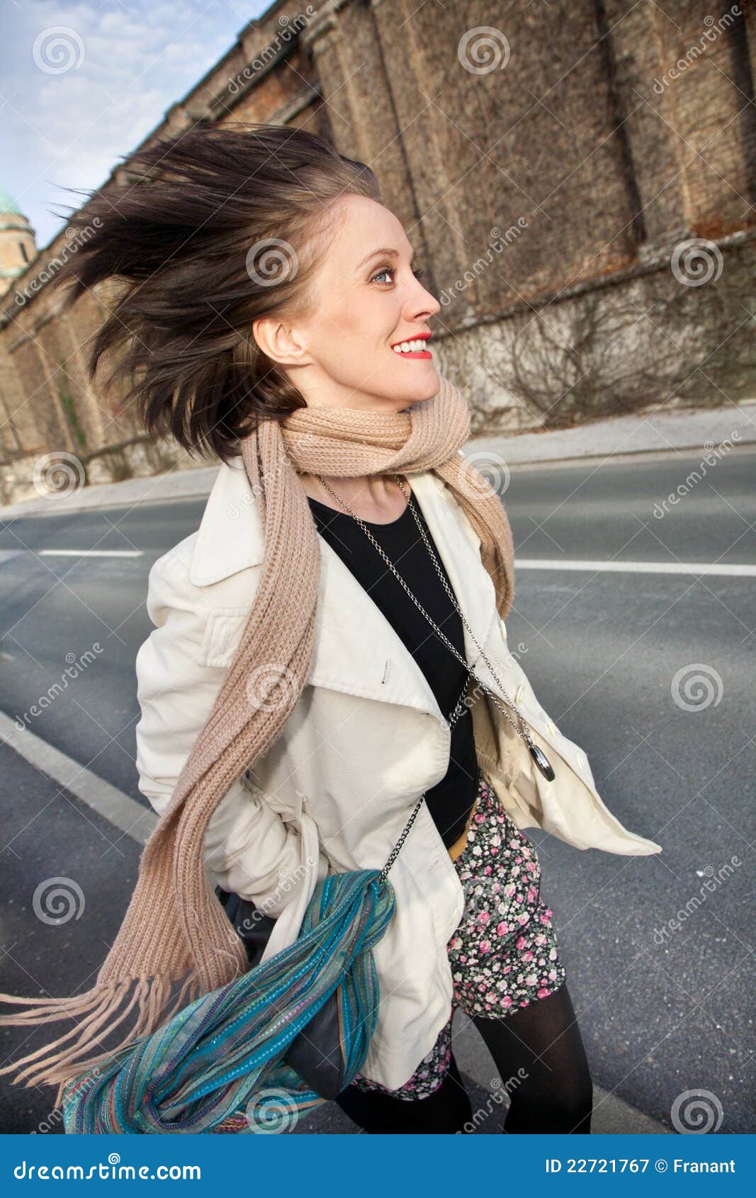Mujer feliz joven que recorre en la acera