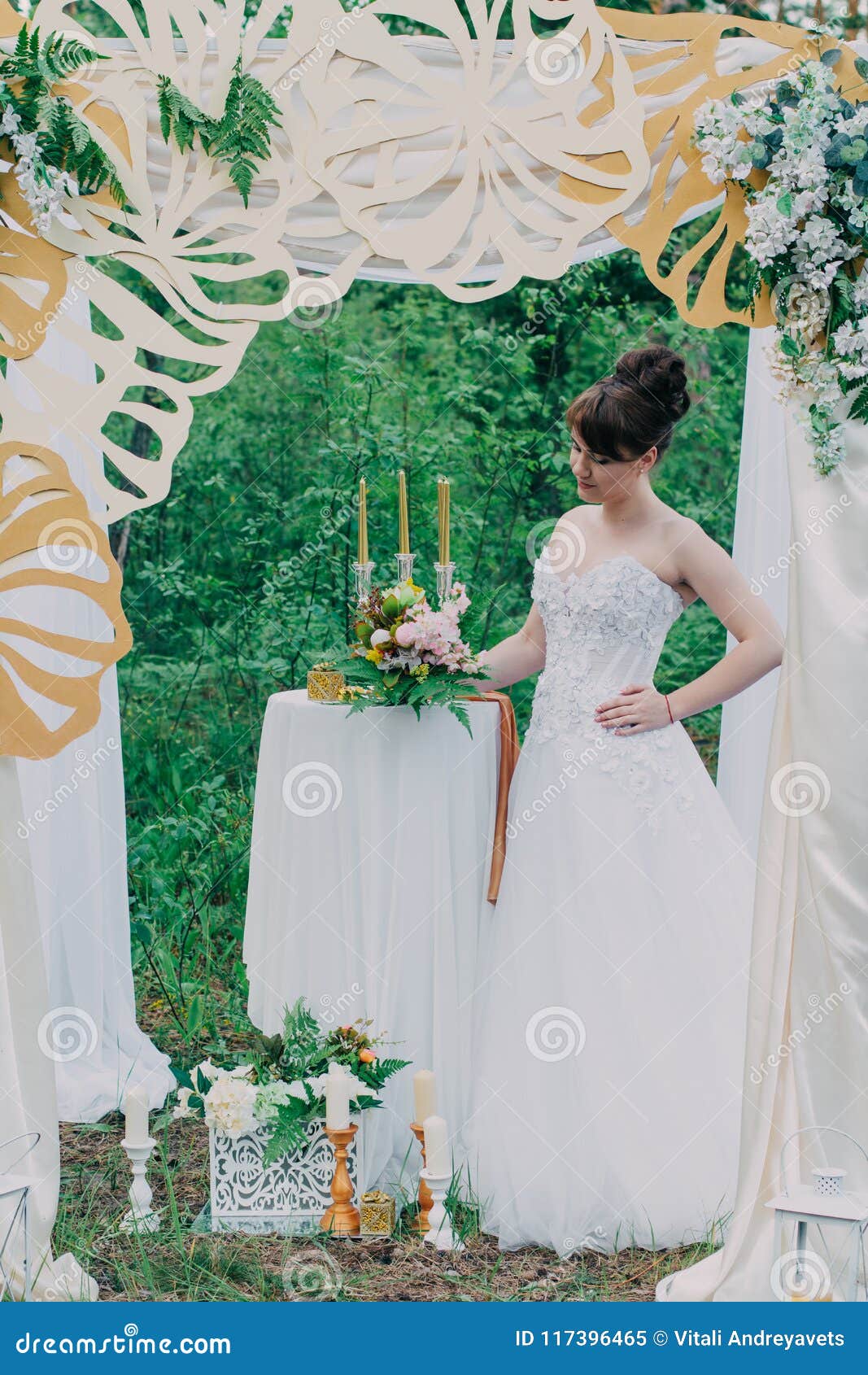 Mujer hermosa en un vestido de boda en un photozone adornado con las flores frescas, la presentación y el retrato